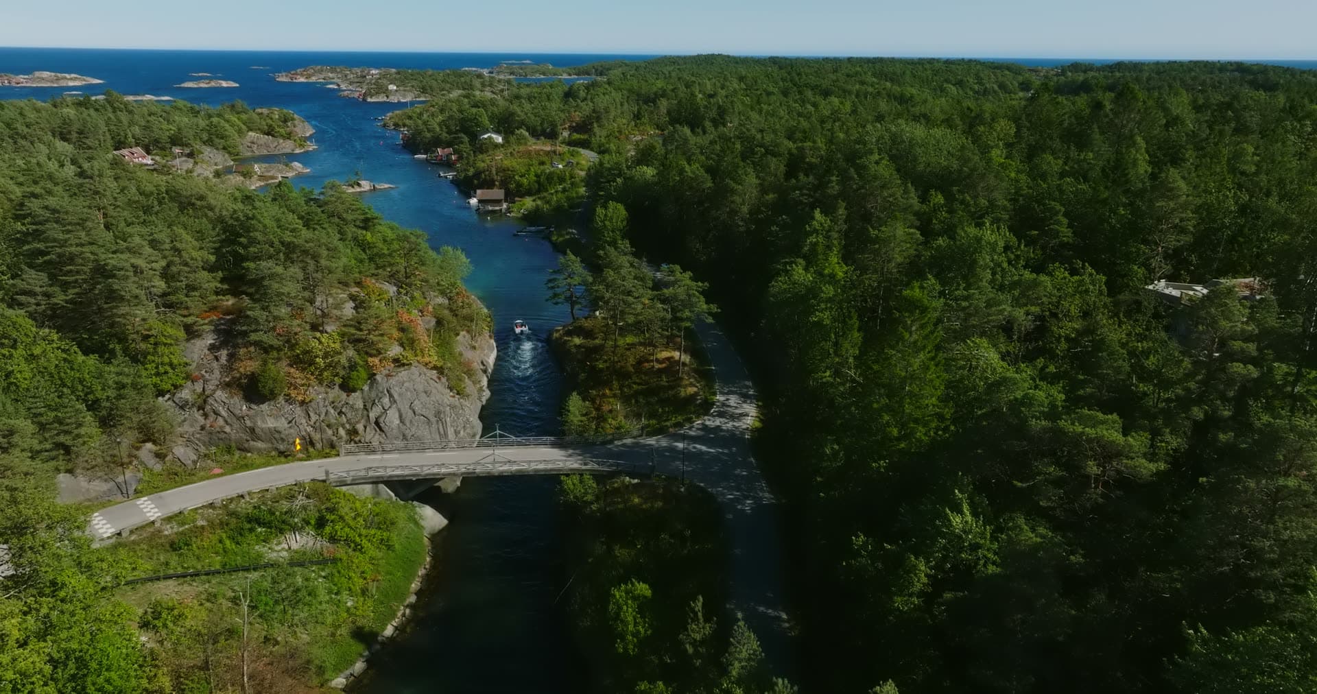 Boat wake below the bridge with cabins beyond, Lillesand, Norway