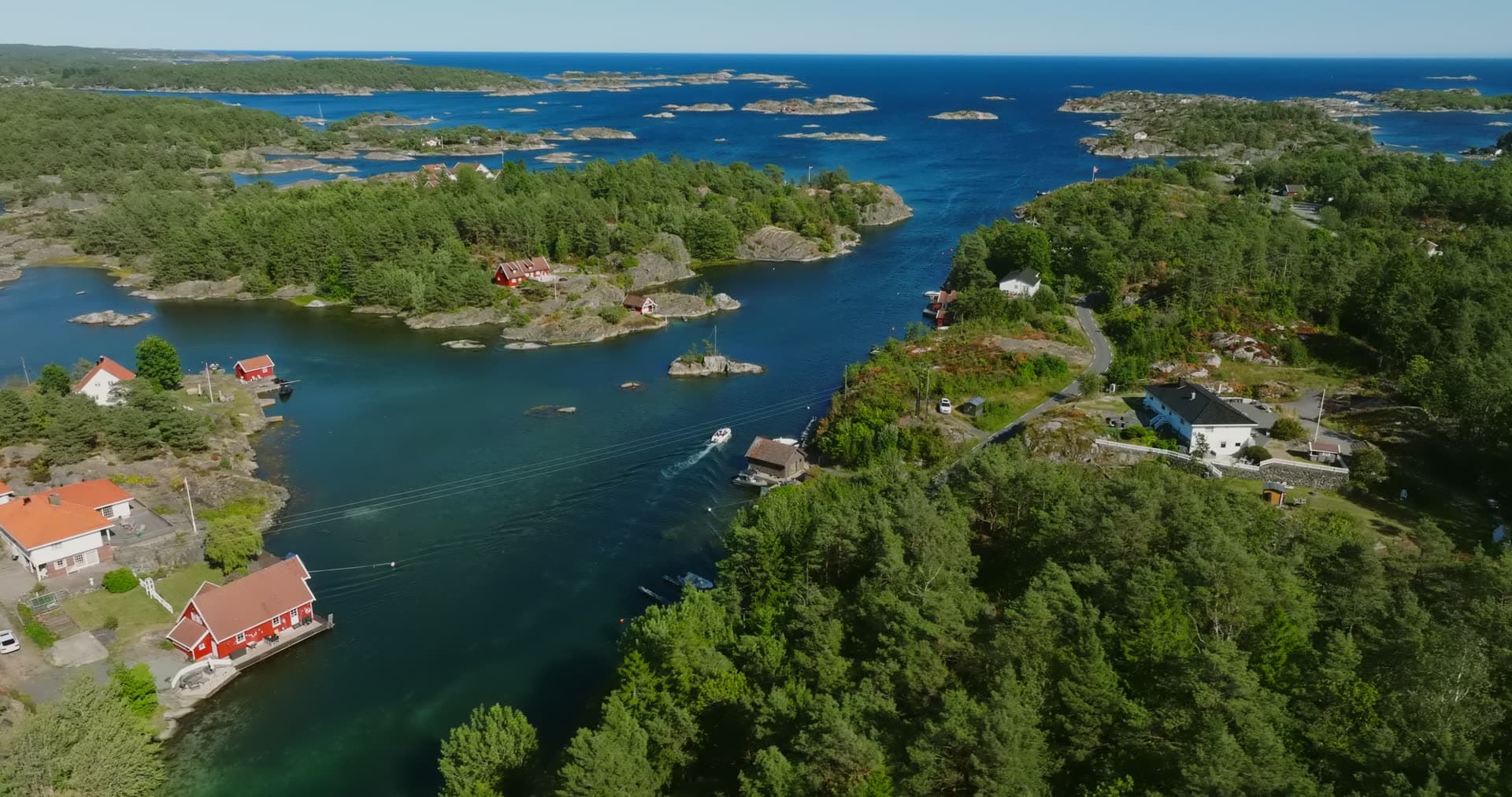 Boat wake between the islets and shore houses, Lillesand, Norway