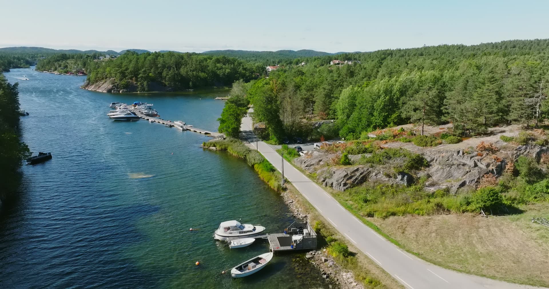 Motorboats at a small dock by the shore road, Lillesand, Norway