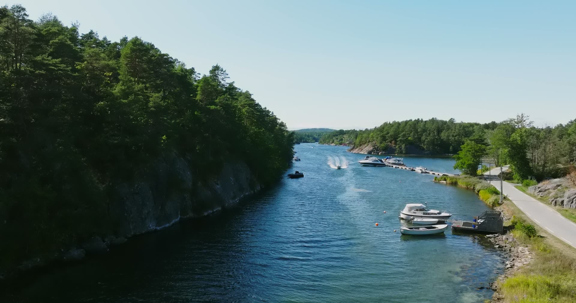 Wooded cliff wall opposite the moored boats, Lillesand, Norway