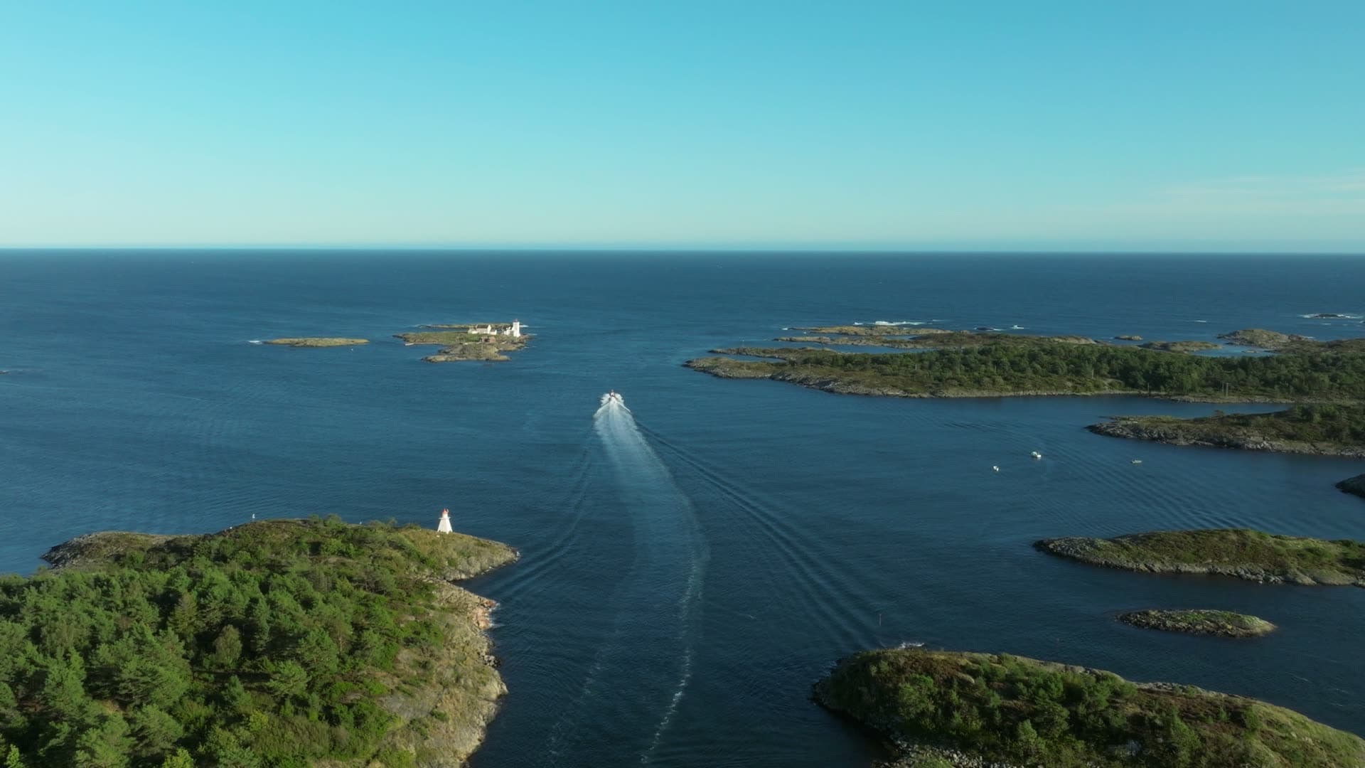 Boat wake past white beacon toward sea, Lillesand, Norway