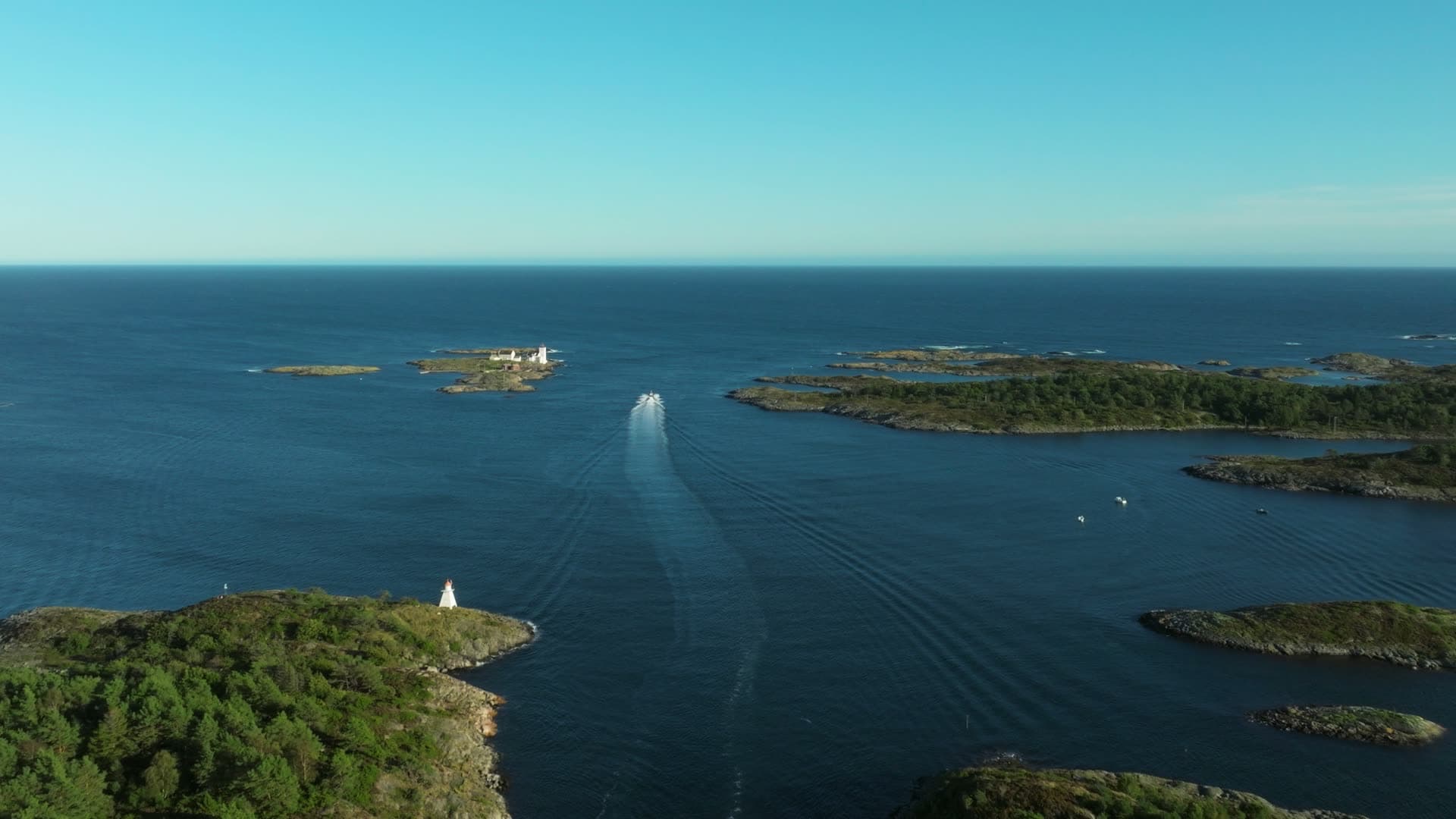 Boat wake past white beacon and skerries, Lillesand, Norway