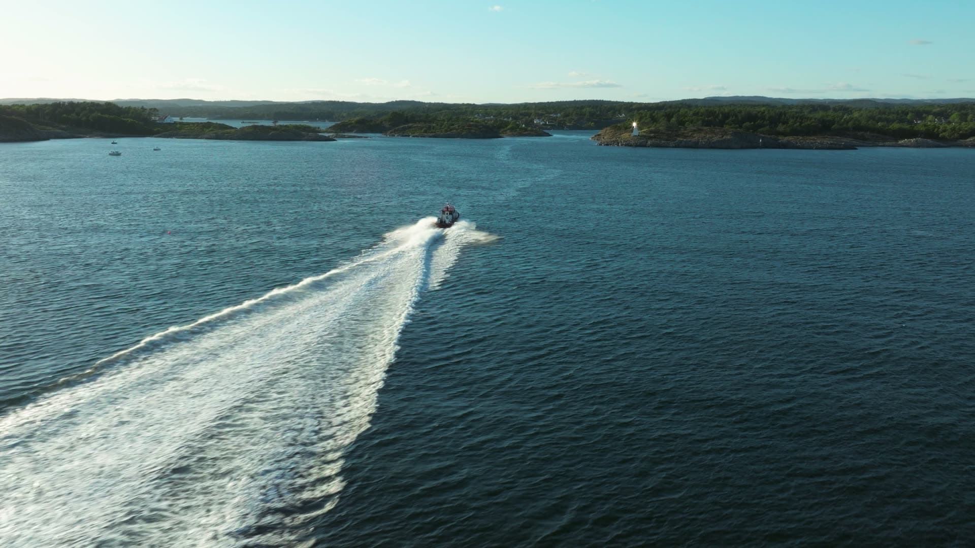Speedboat wake trailing past wooded islets, Lillesand, Norway