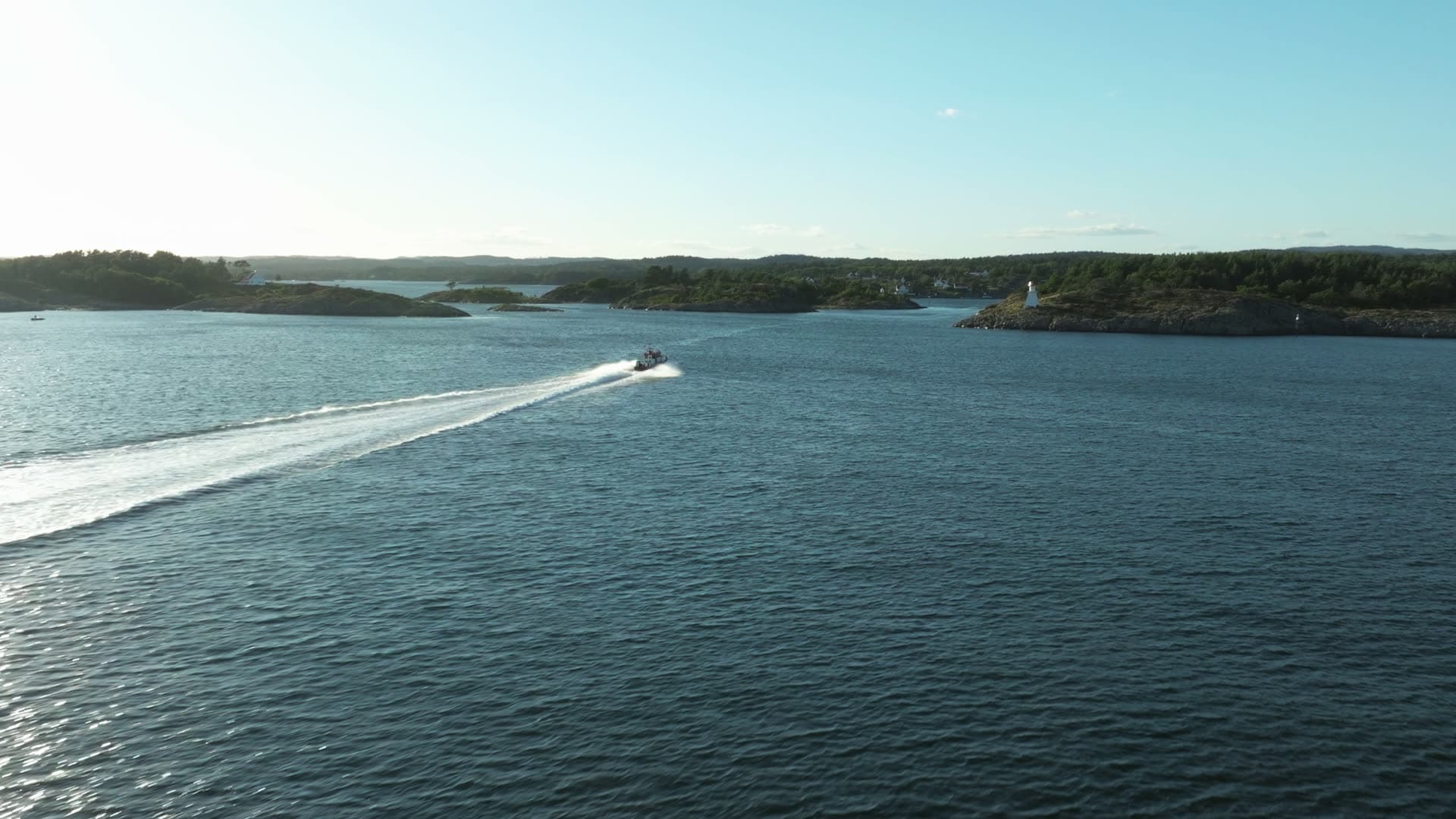 Speedboat wake toward small lighthouse, Lillesand, Norway