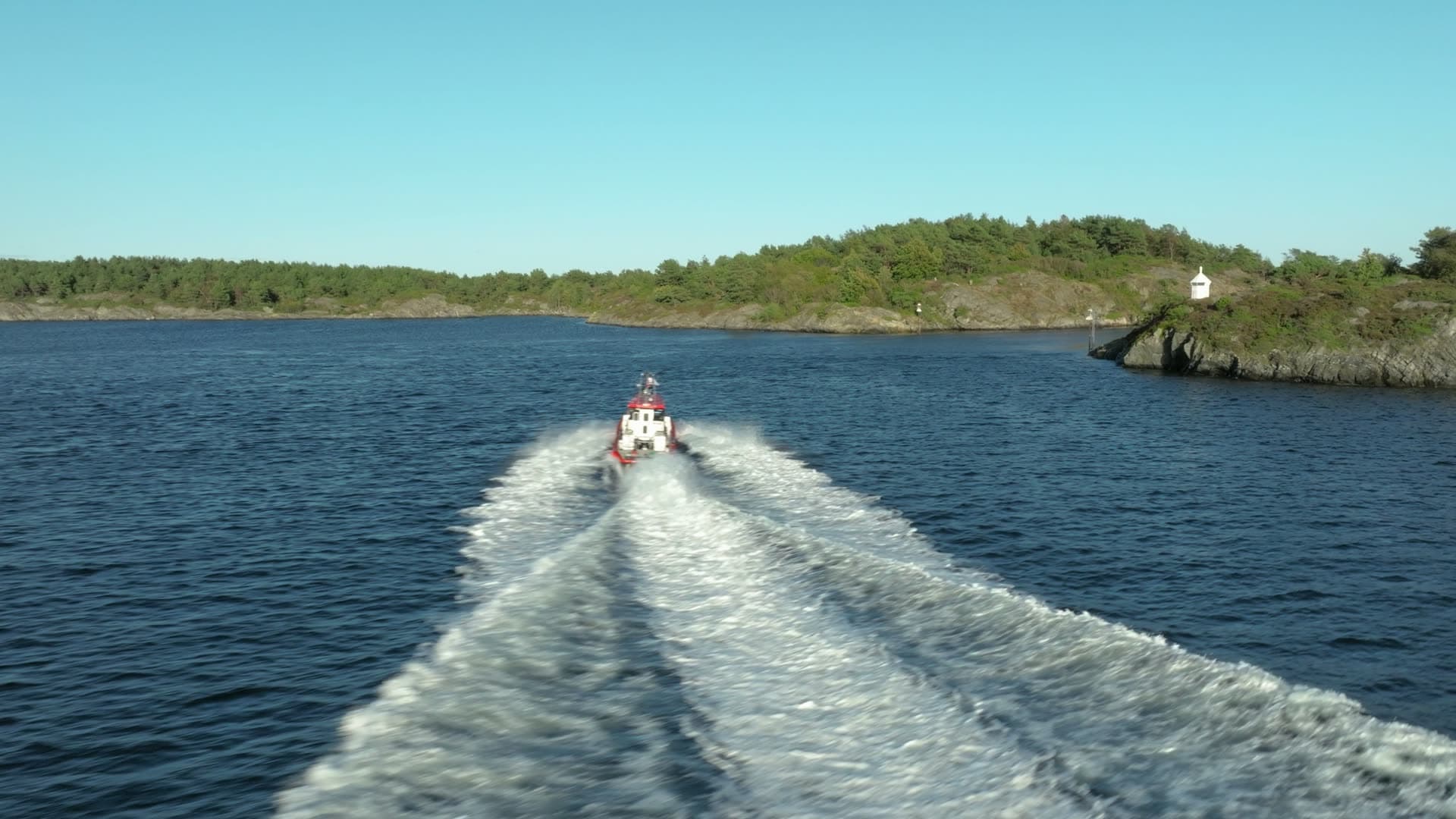 Red pilot boat wake past small beacon, Lillesand, Norway