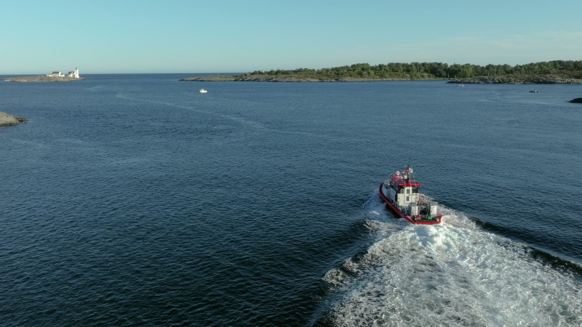 Red pilot boat trailing wake past islets, Lillesand, Norway