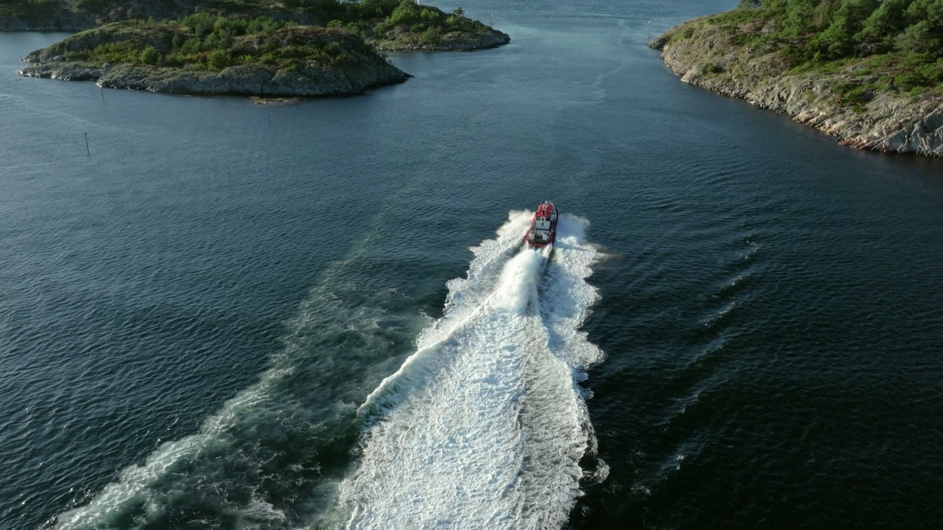Red pilot boat wake between rocky islets, Lillesand, Norway