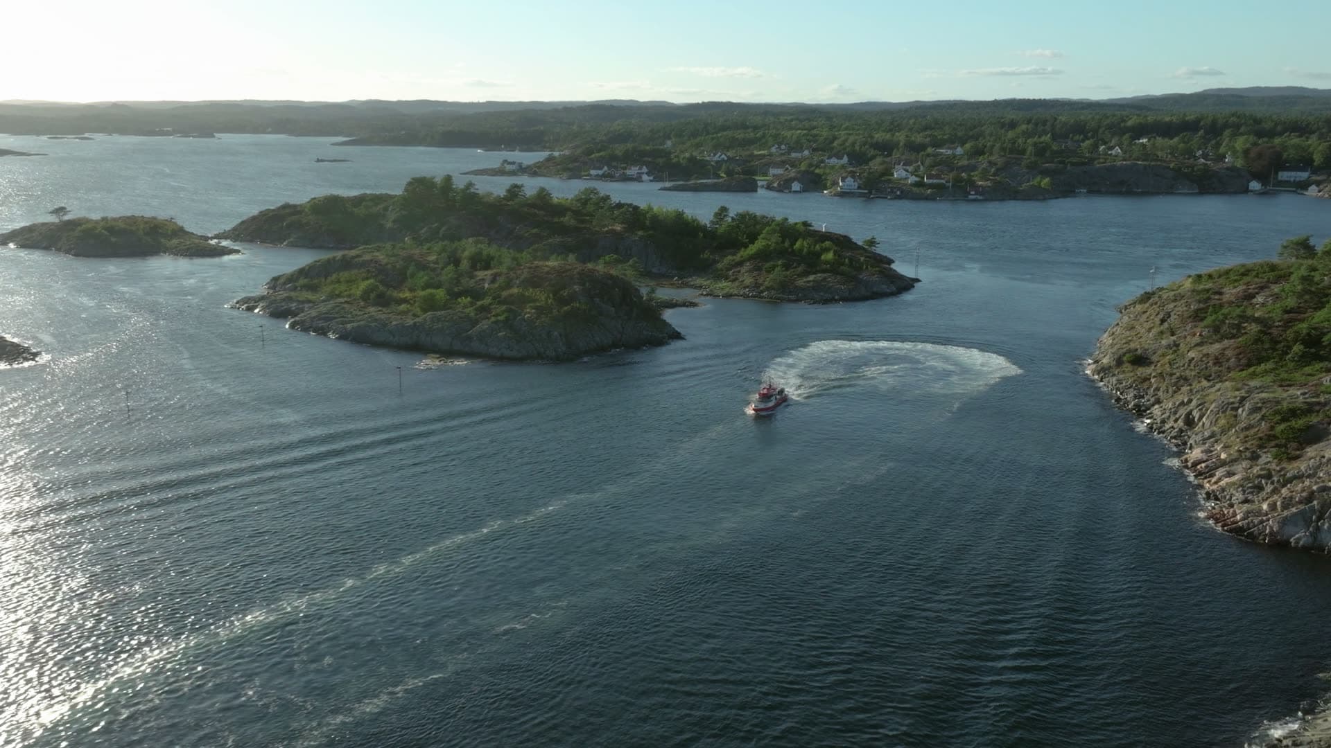 Boat carving a wide wake between islets, Lillesand, Norway