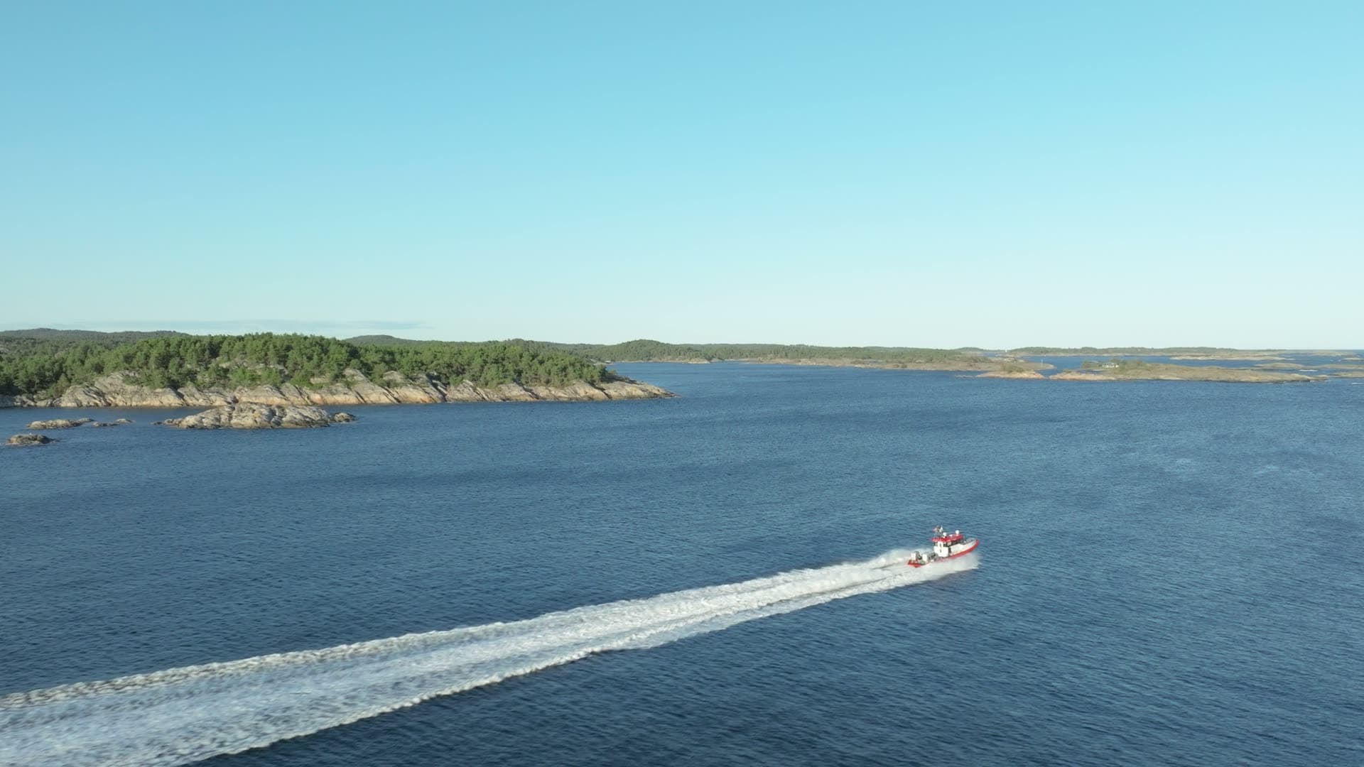 Red RIB carving a curved wake past islets, Lillesand, Norway