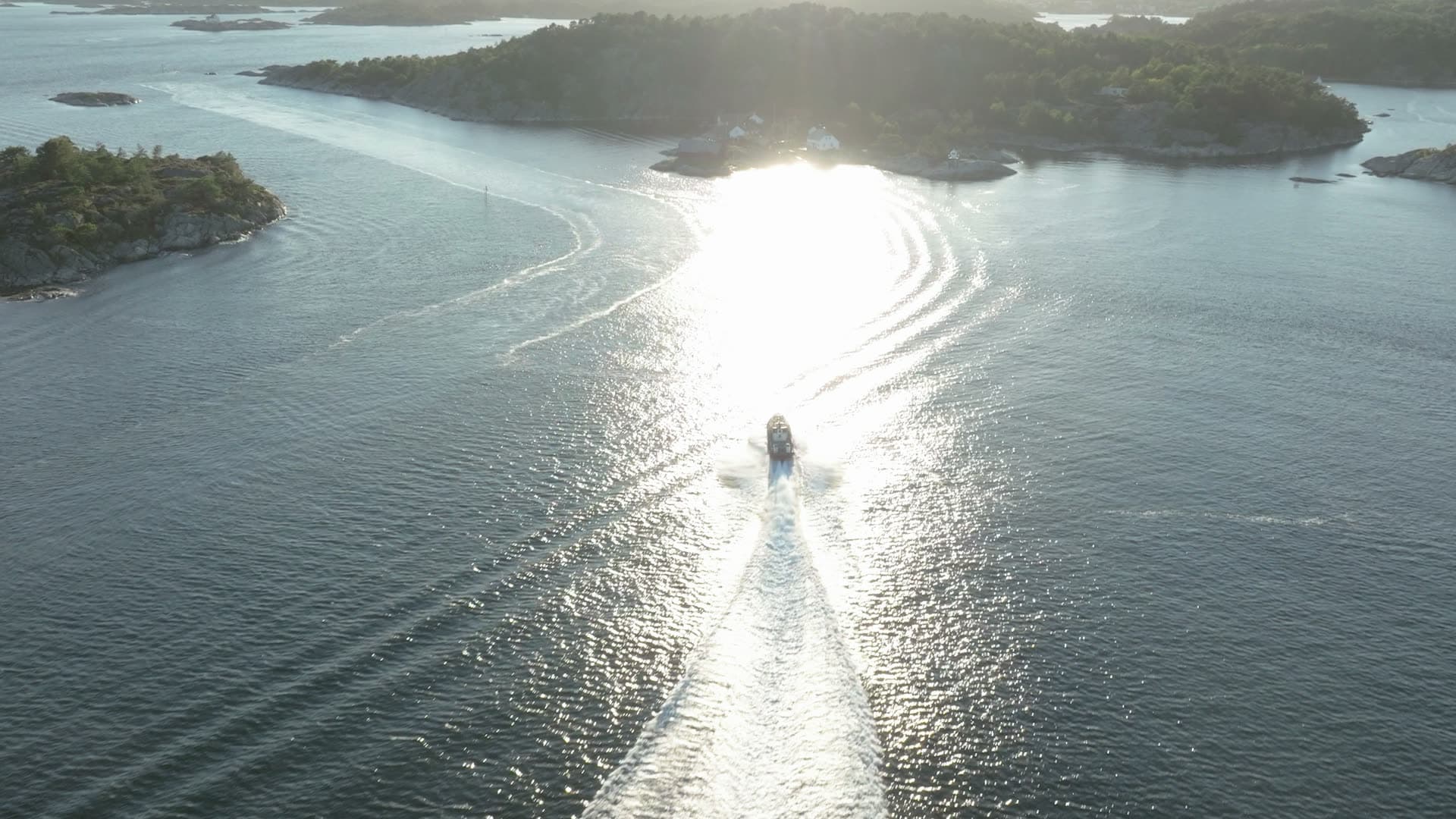 Speedboat wake into backlit island strait, Lillesand, Norway