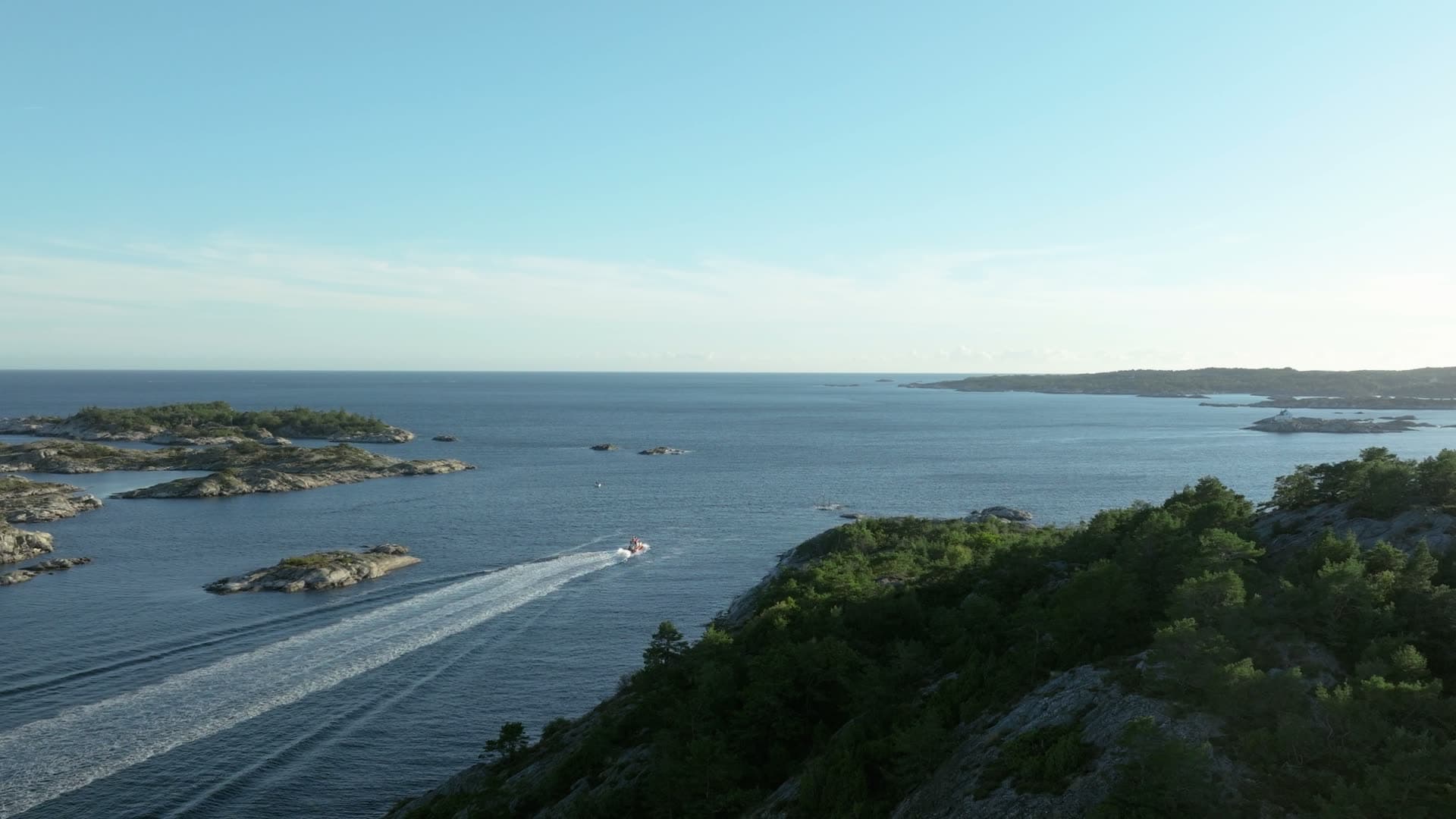Speedboat wake past rocky wooded islets, Lillesand, Norway