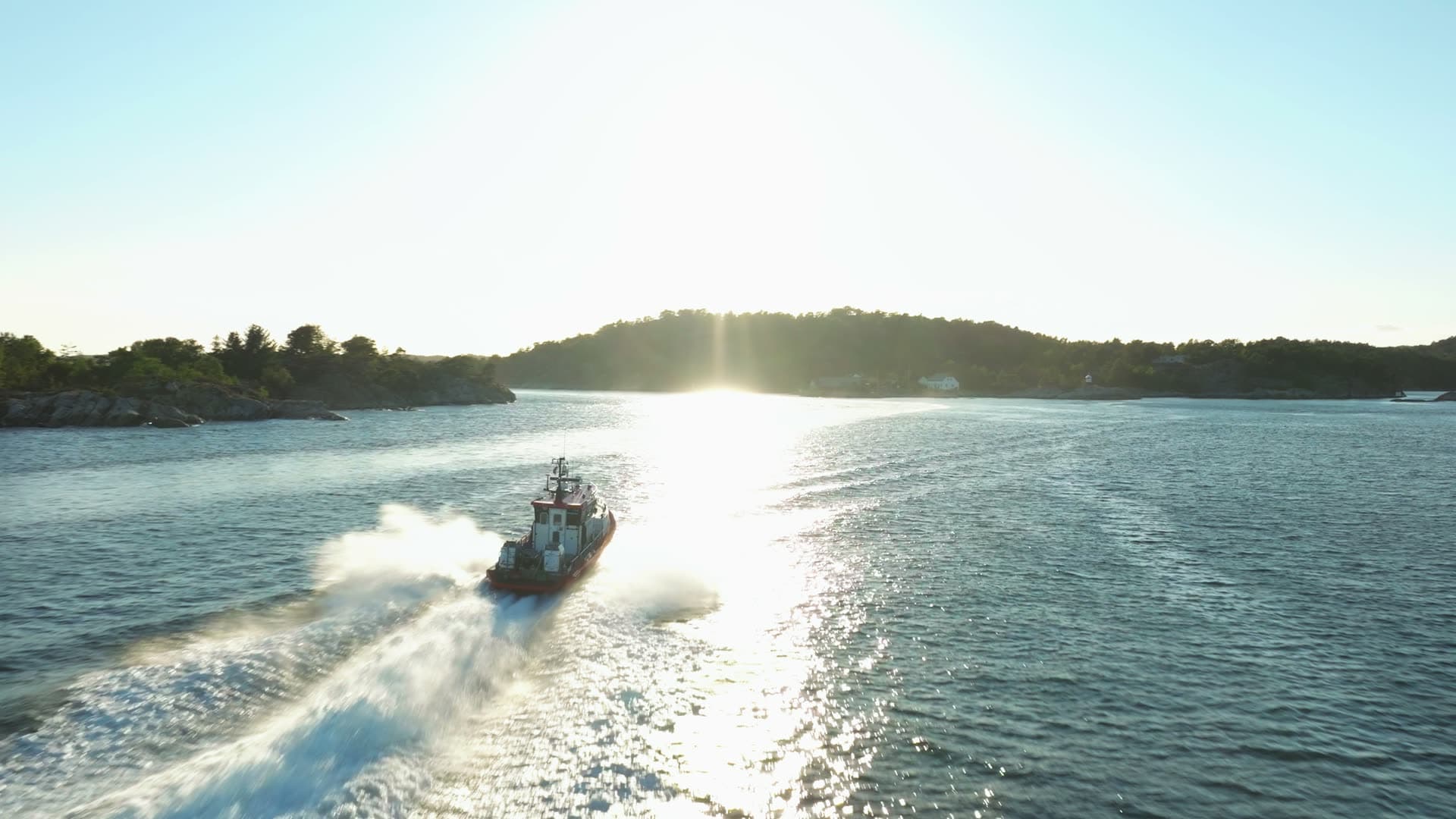 Workboat throwing spray into low sun, Lillesand, Norway