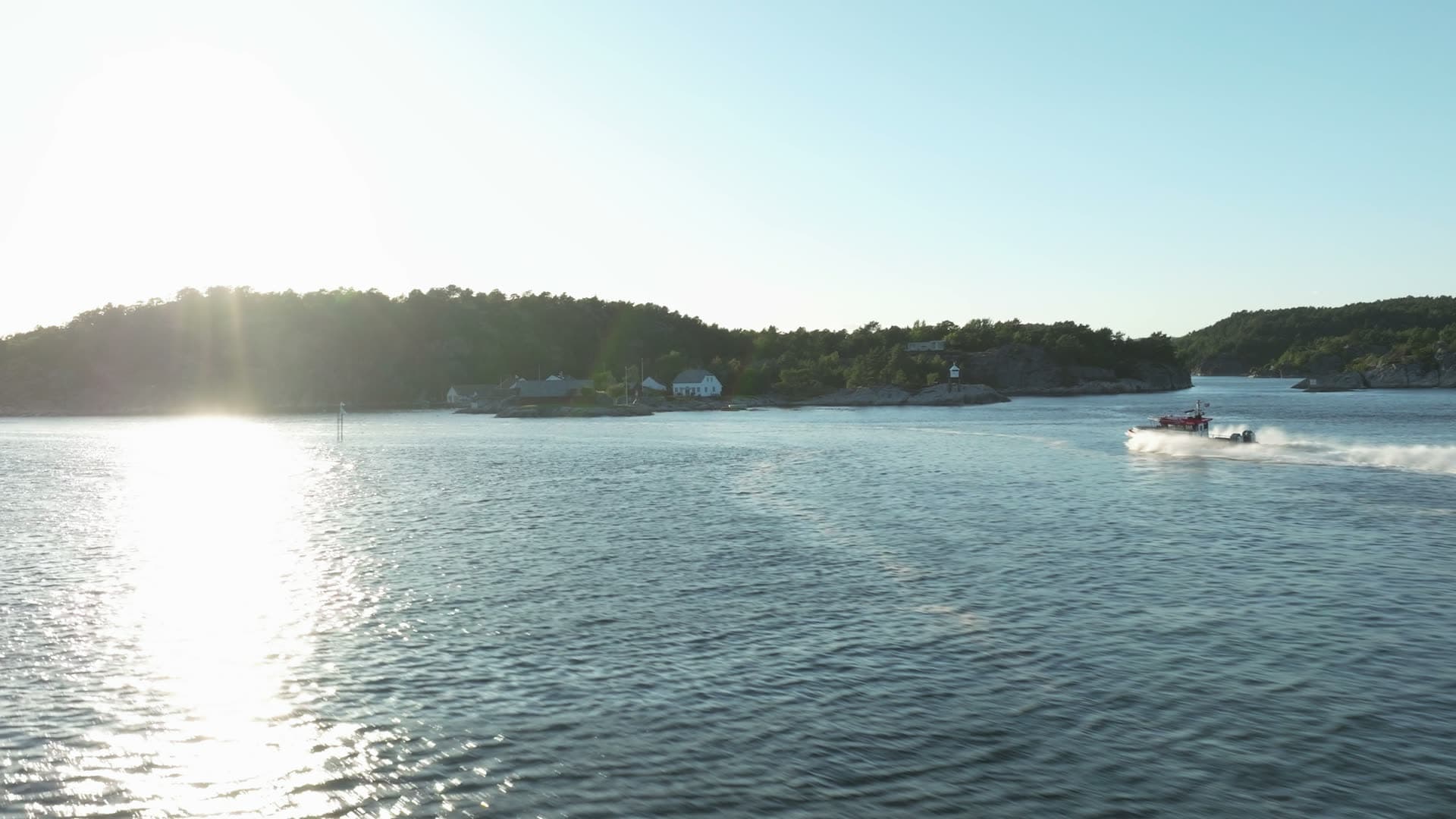 Speedboat wake past white houses on shore, Lillesand, Norway