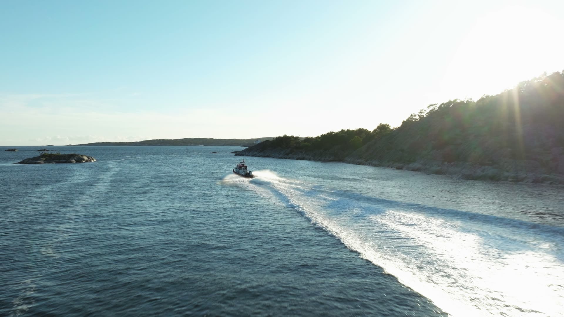 Speedboat wake past wooded headland, Lillesand, Norway