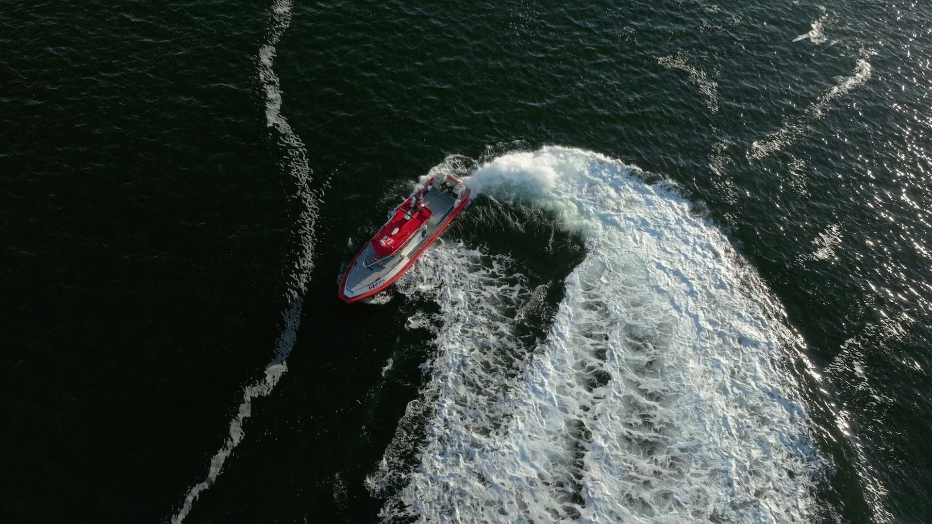 Red rescue boat carving a foaming U-turn, Lillesand, Norway