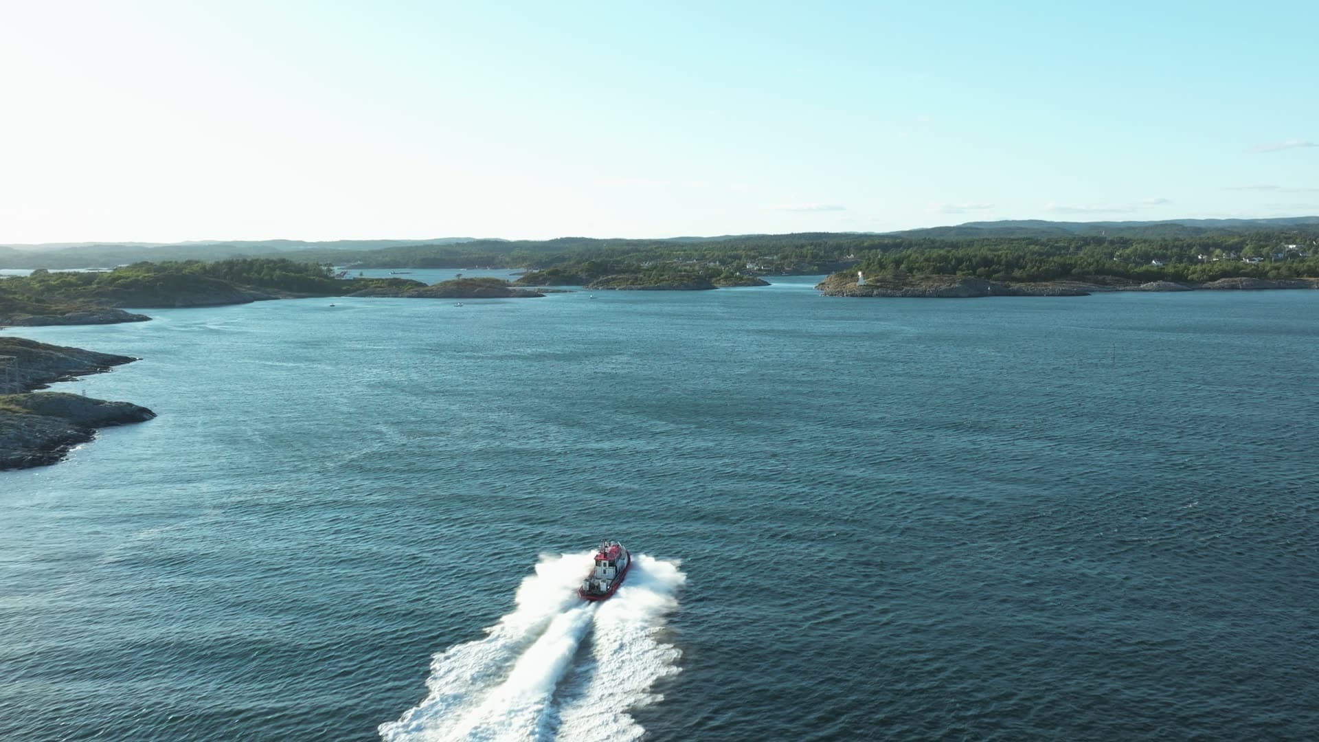 RIB speedboat carving wake past wooded islets, Lillesand, Norway