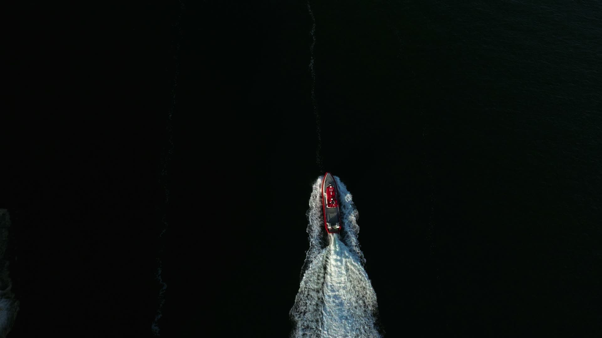 Red RIB carving a wake on dark water, Lillesand, Norway