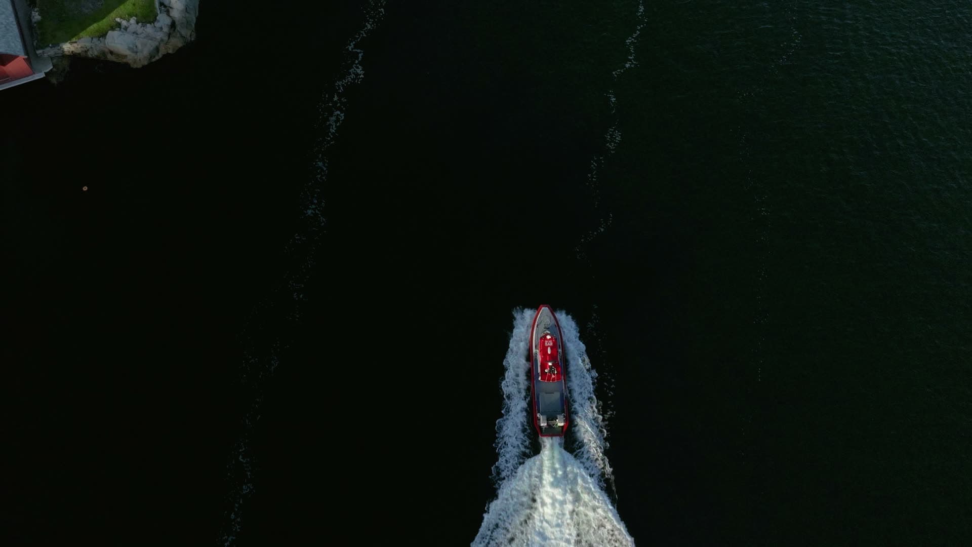 Red RIB carving wake on dark water, Lillesand, Norway