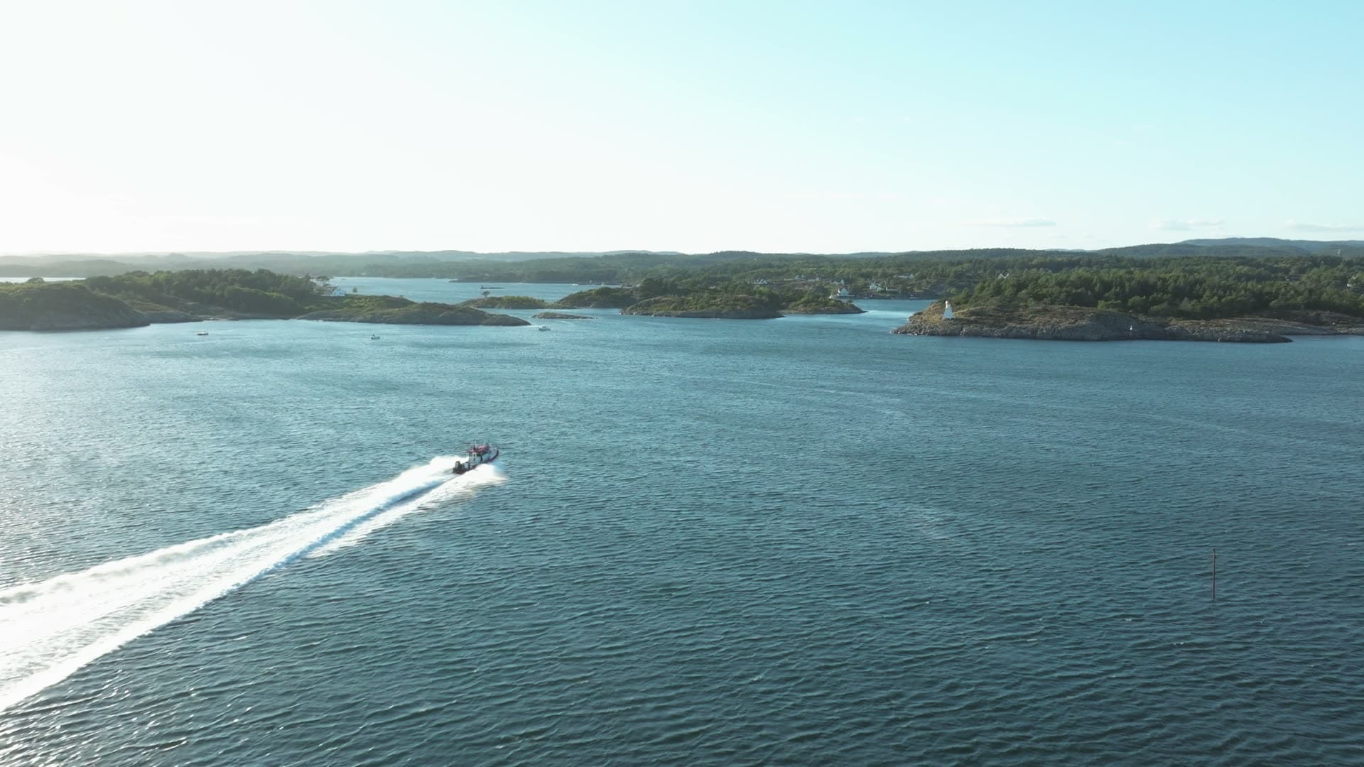 Speedboat wake between wooded islets, Lillesand, Norway
