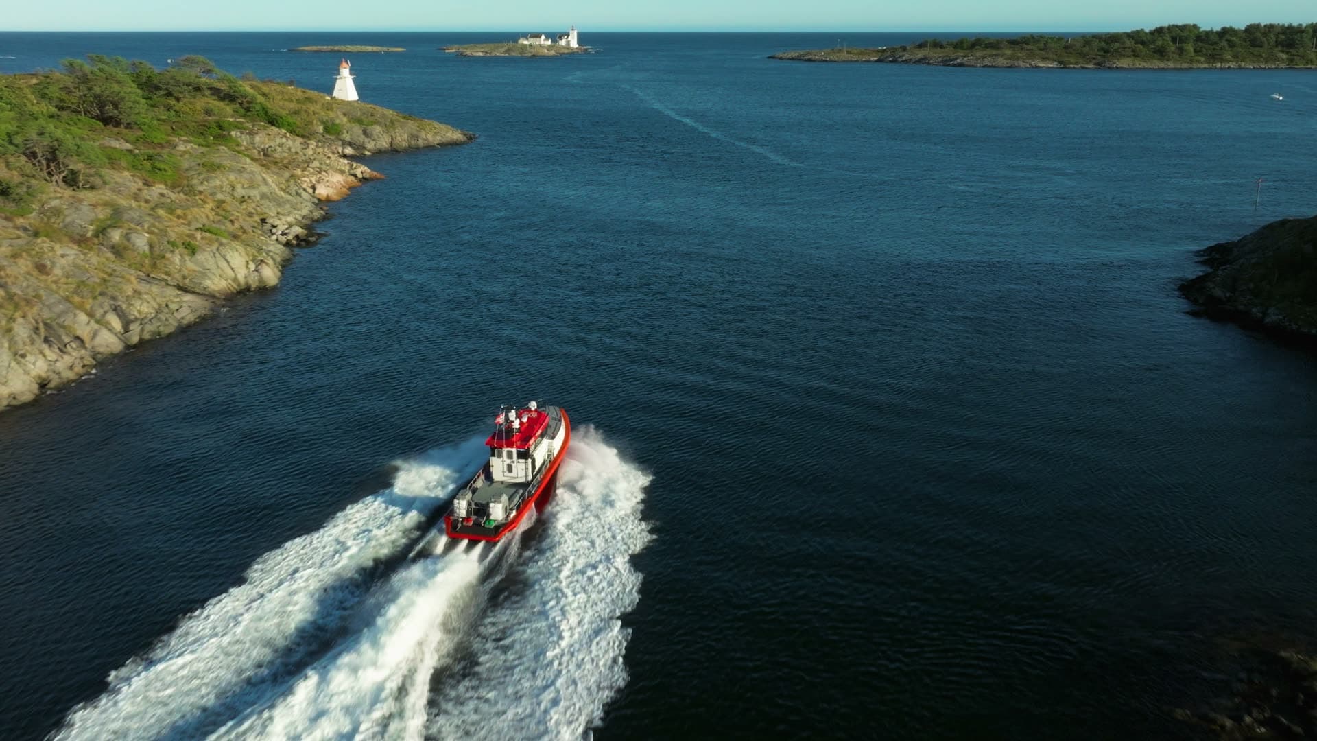 Red pilot boat speeding past beacon, Lillesand, Norway