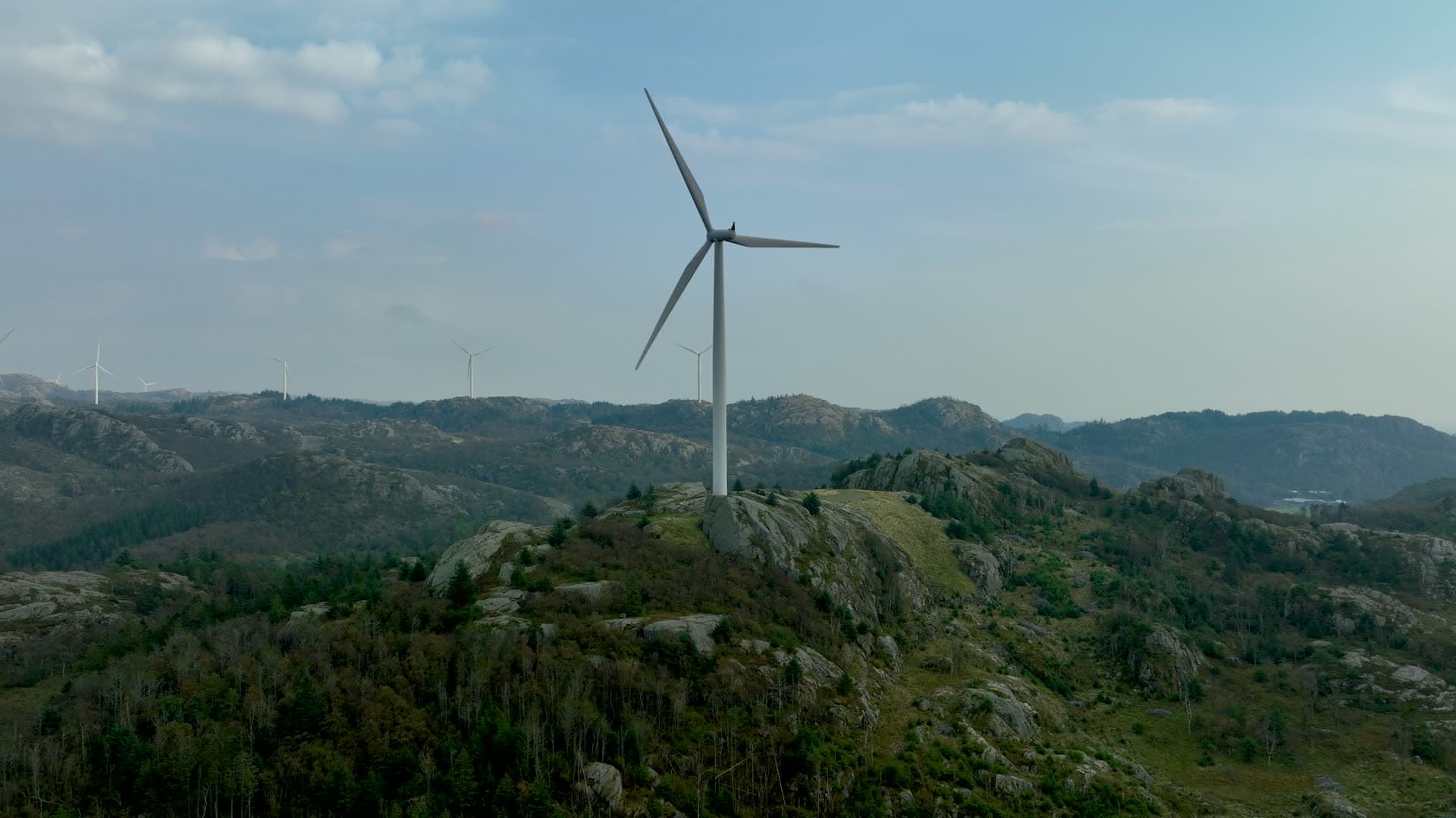 Wind turbine on rocky ridge, more beyond, Lista, Norway