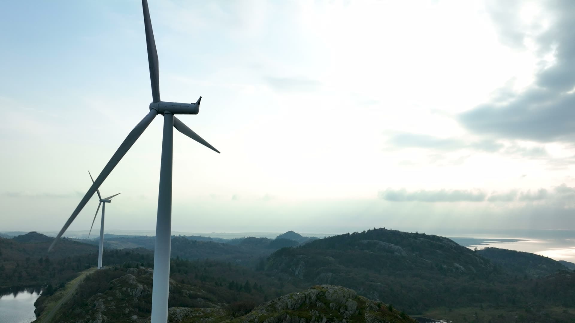 Wind turbines on rocky ridge above lake, Lista, Norway