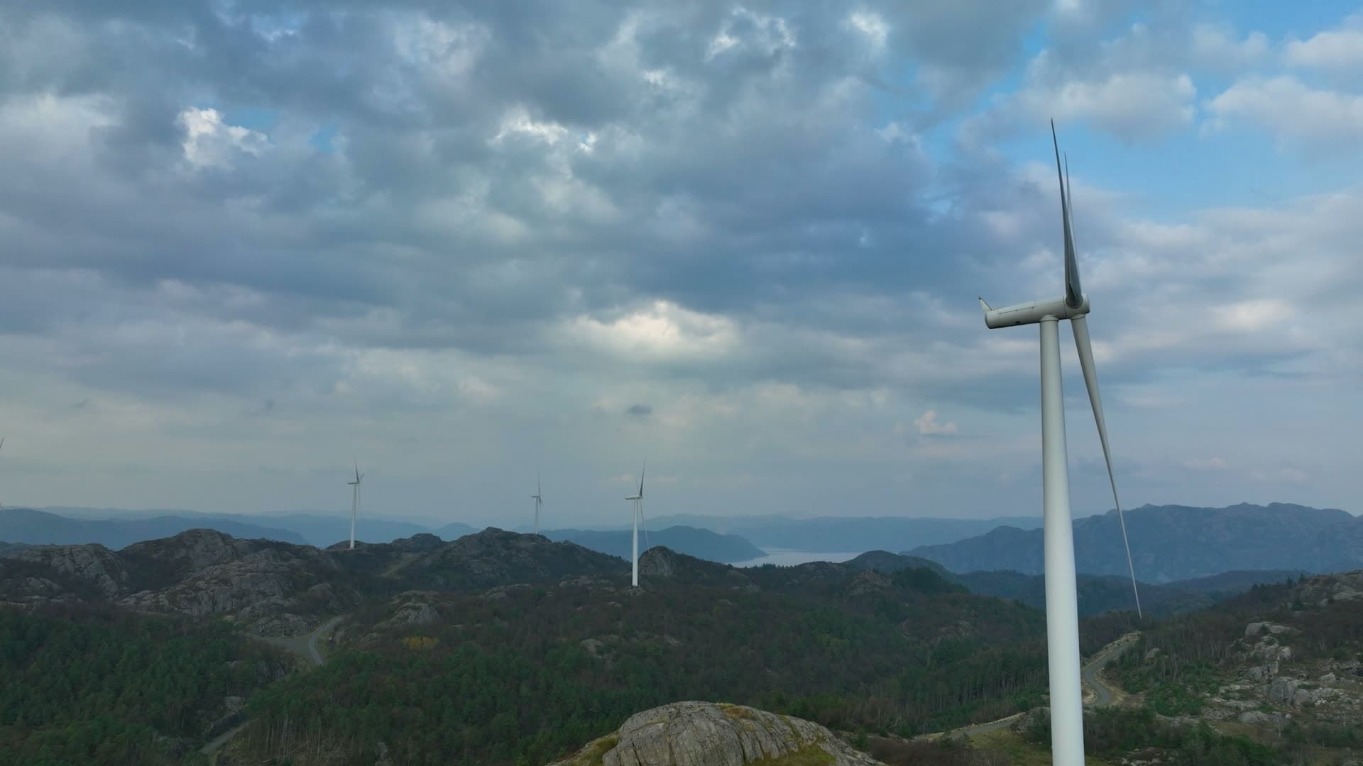 Passing wind turbine on forested ridge, Lista, Norway