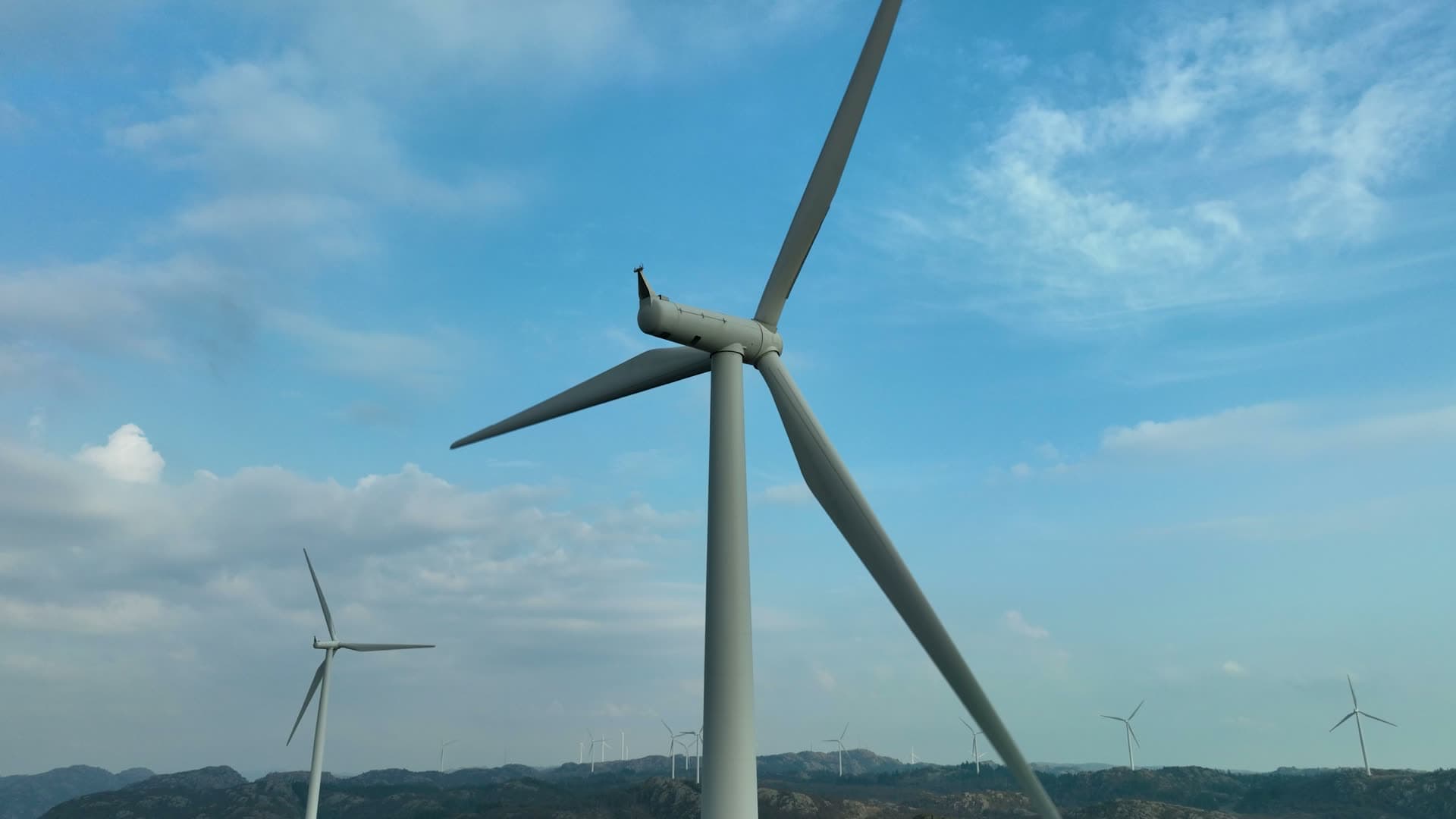 Wind turbine nacelle close-up over rocky hills, Lista, Norway