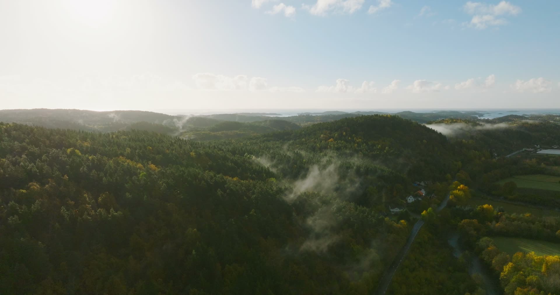 Mist drifting over forest hills and farm road, Monan, Norway