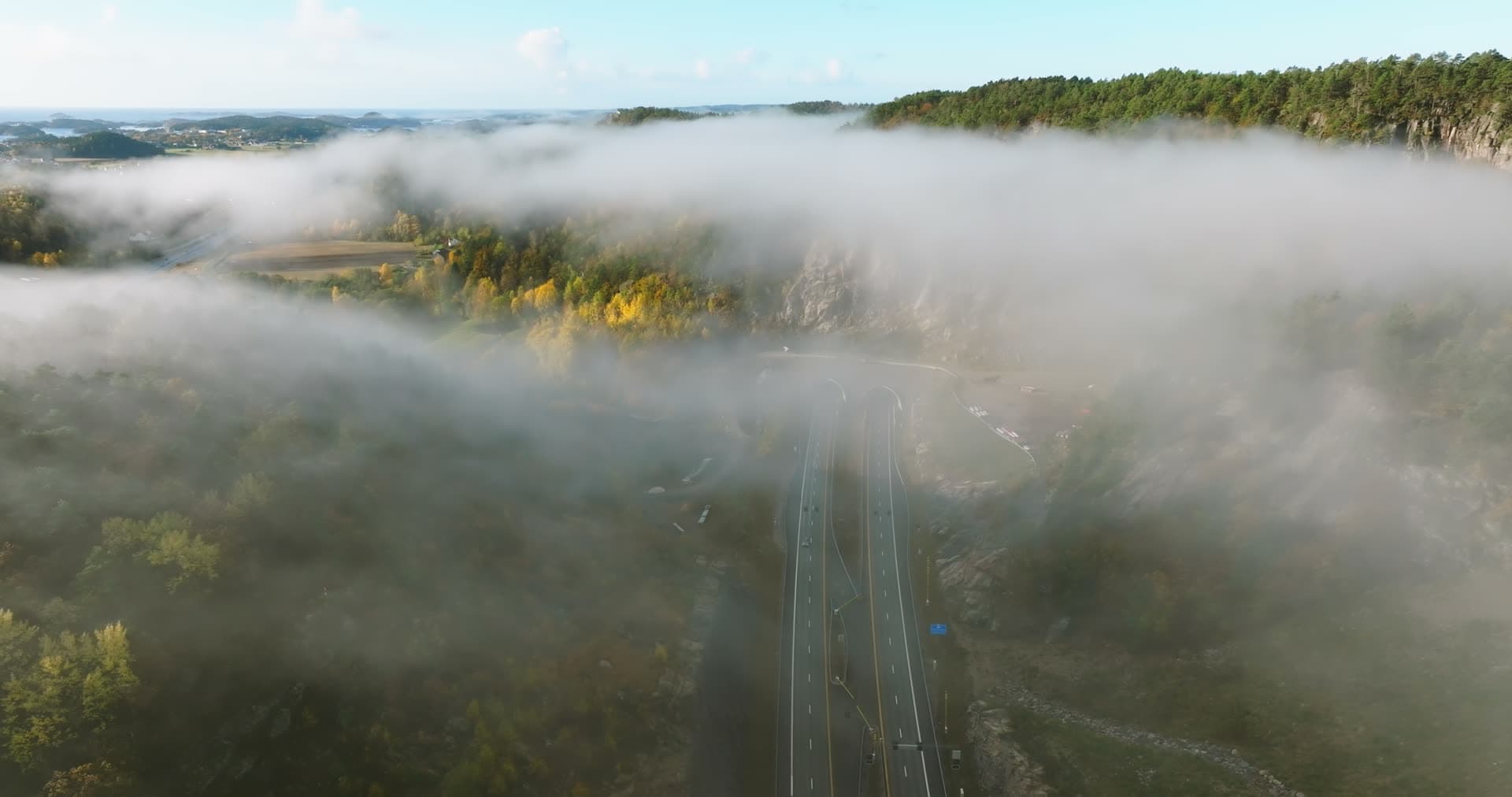 Fog drifting over highway cut in rock, Monan, Norway