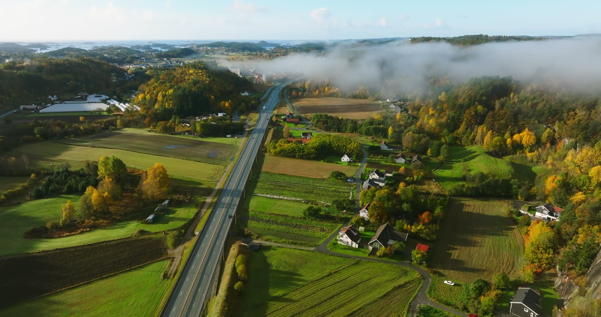 Highway through farmland under low fog, Monan, Norway