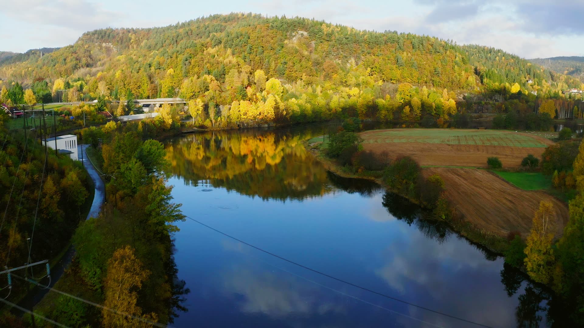 Still river below autumn hill and plowed field, Mosby, Norway