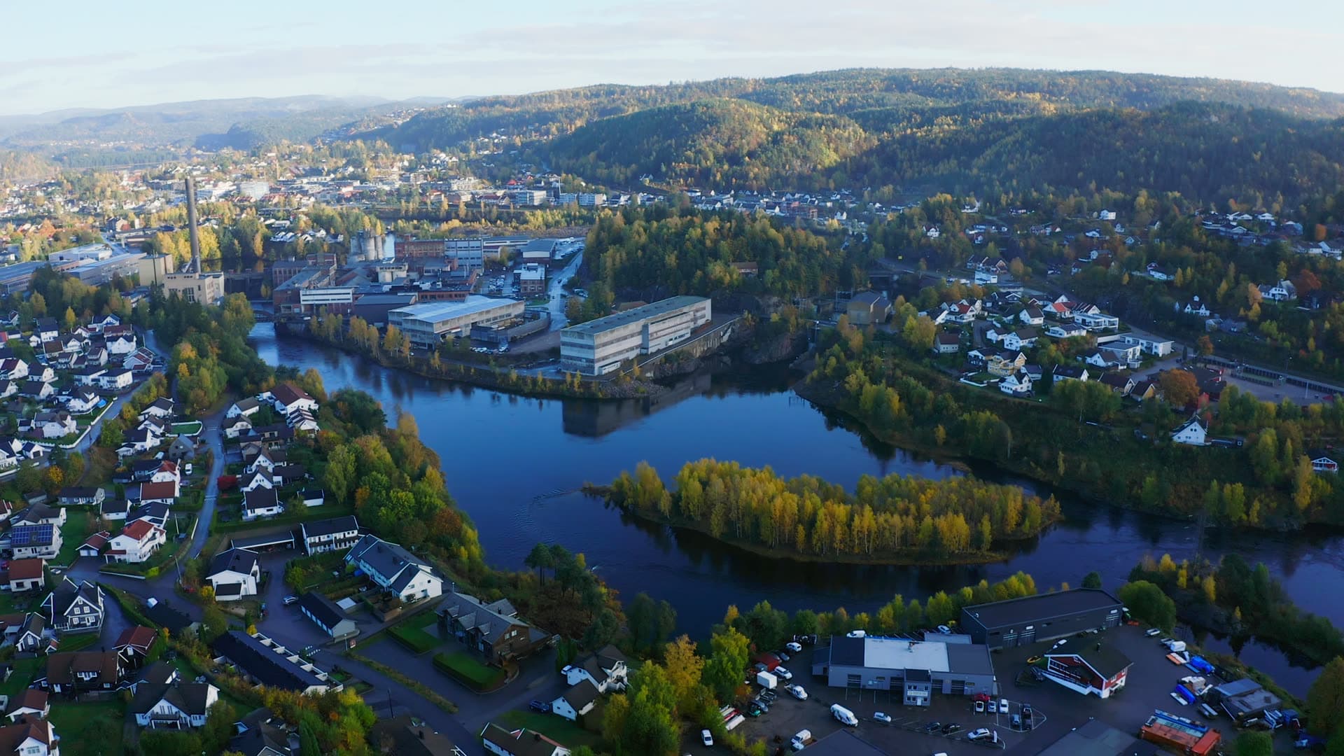Riverside factory with chimney by wooded islet, Moseidmoen, Norway