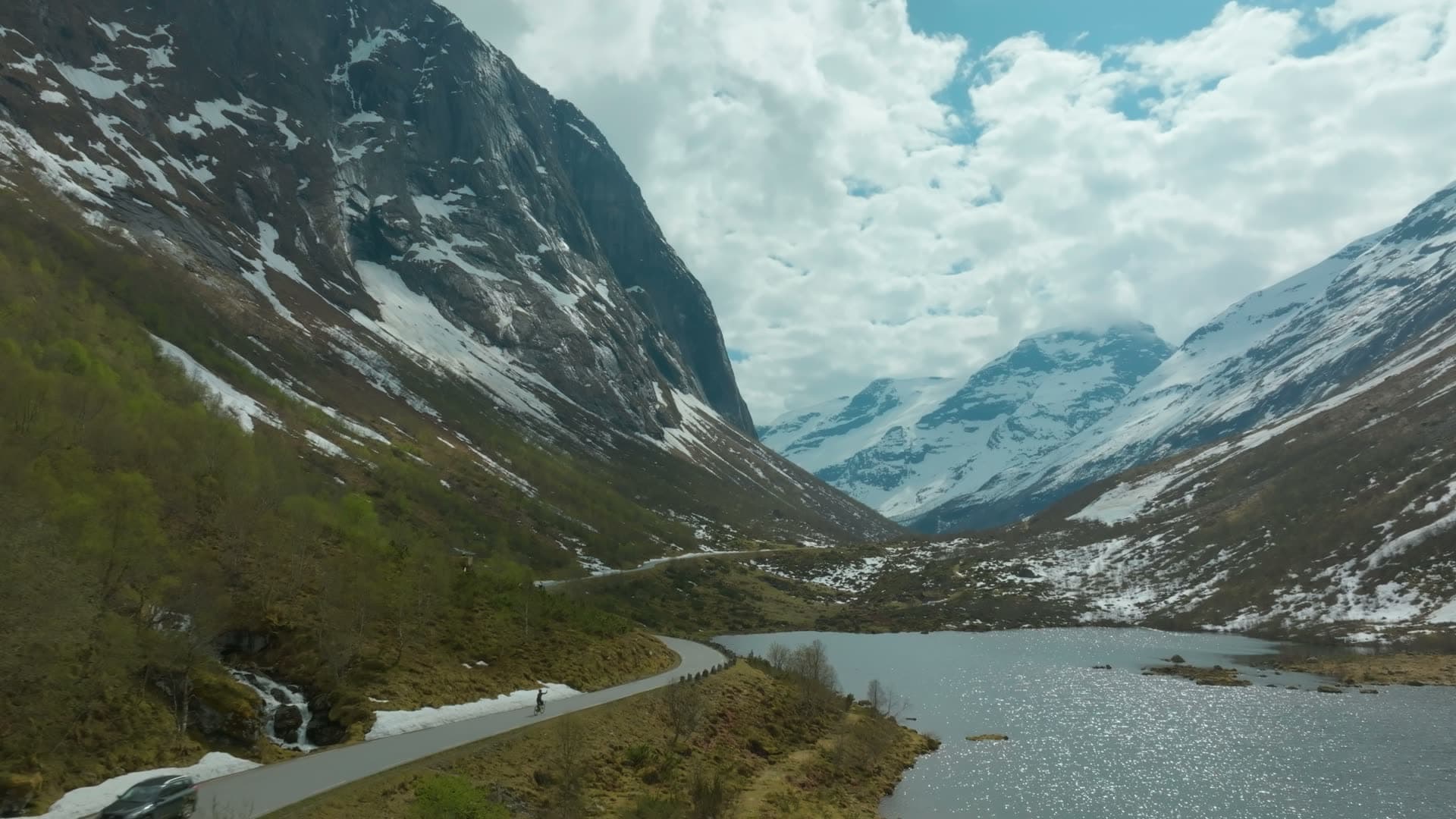 Cyclist on valley road beside lake, Norangsdalen, Norway