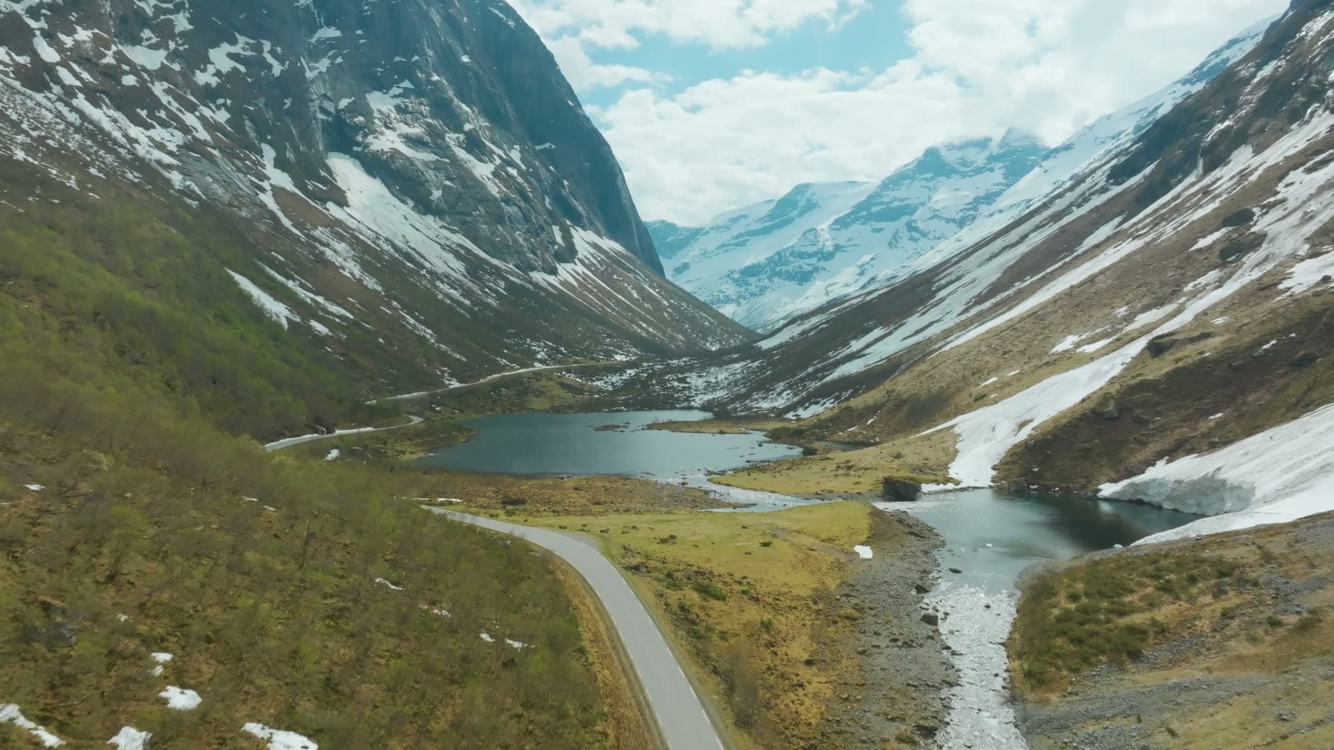 Road along valley lake below snowy peaks, Norangsdalen, Norway