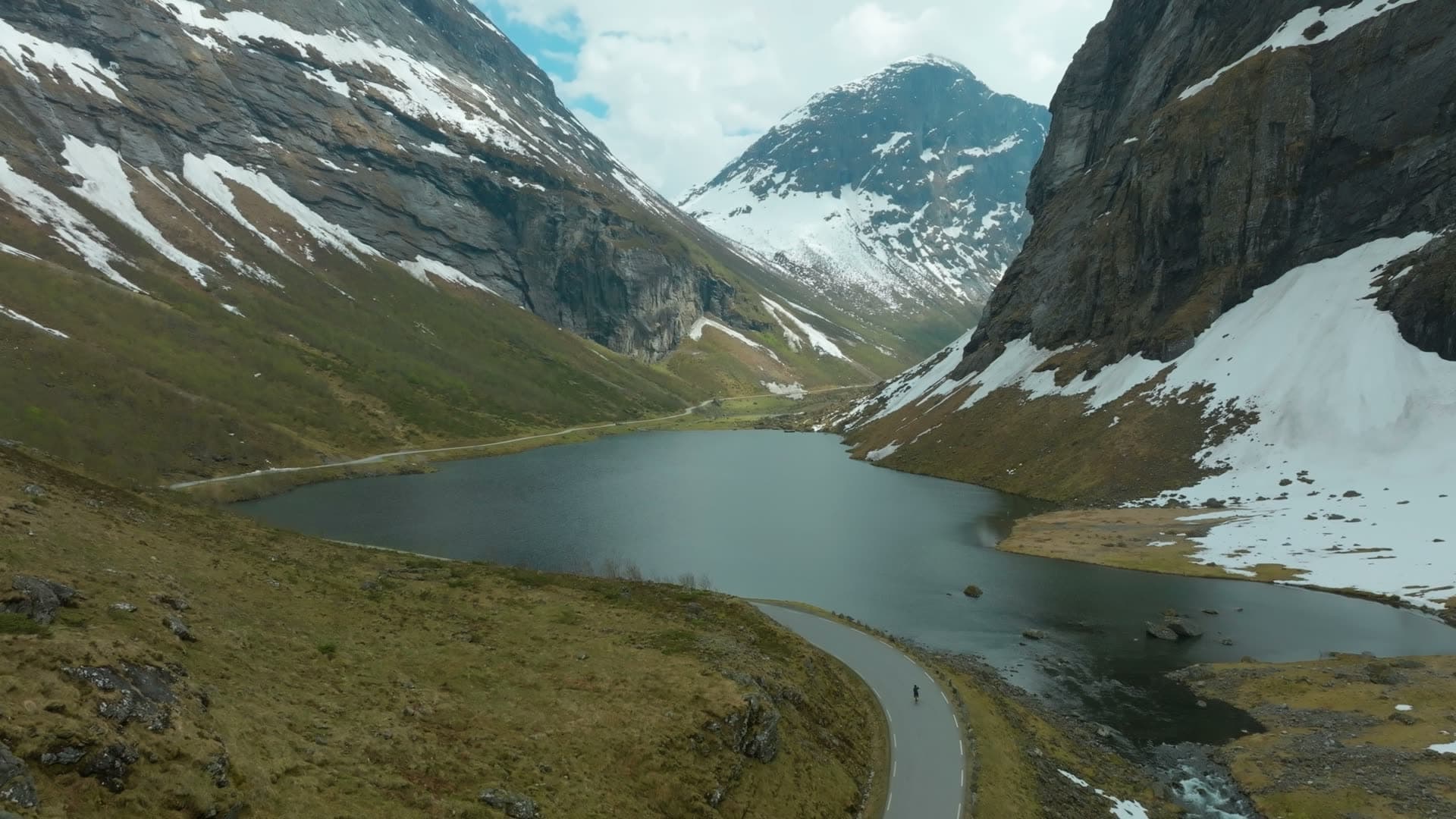 Lone cyclist on road by mountain lake, Norangsdalen, Norway