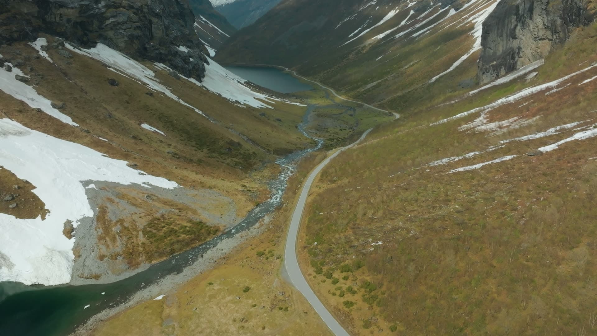Road and braided river past snow patches, Norangsdalen, Norway