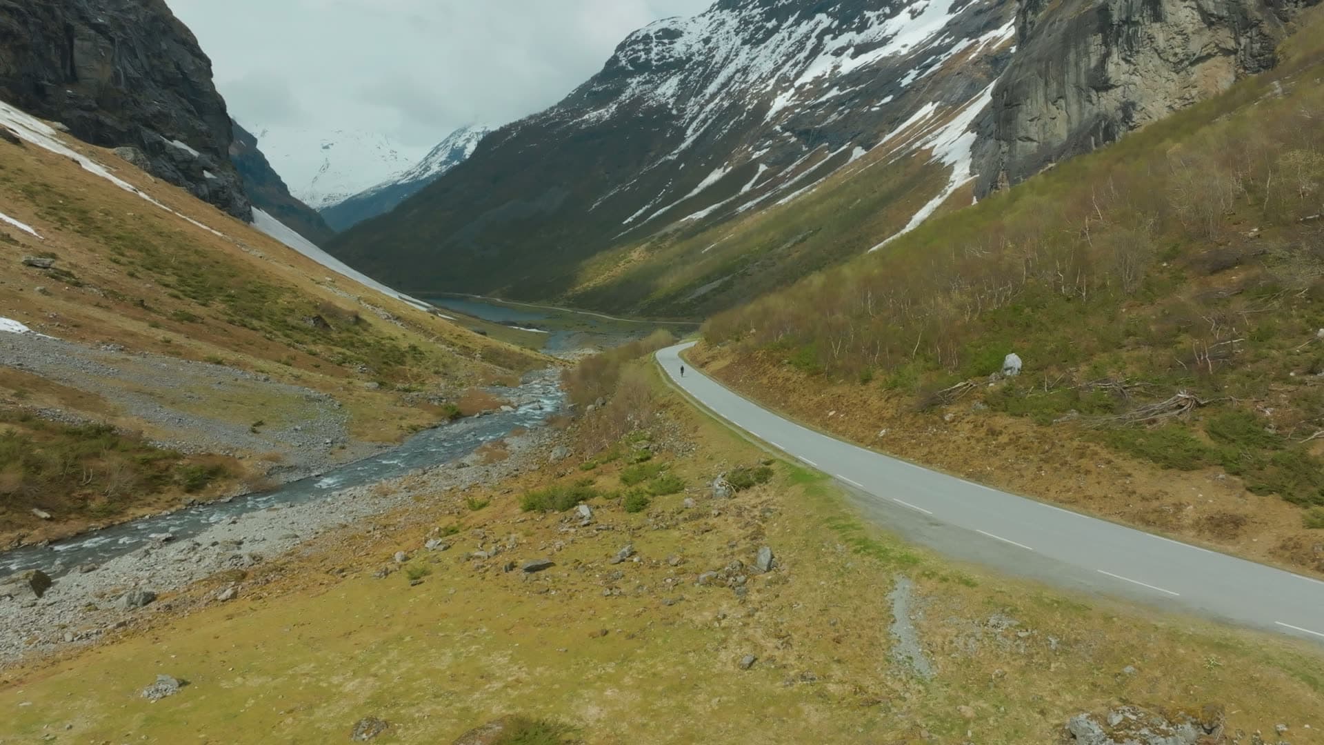 Lone cyclist on valley road by river, Norangsdalen, Norway