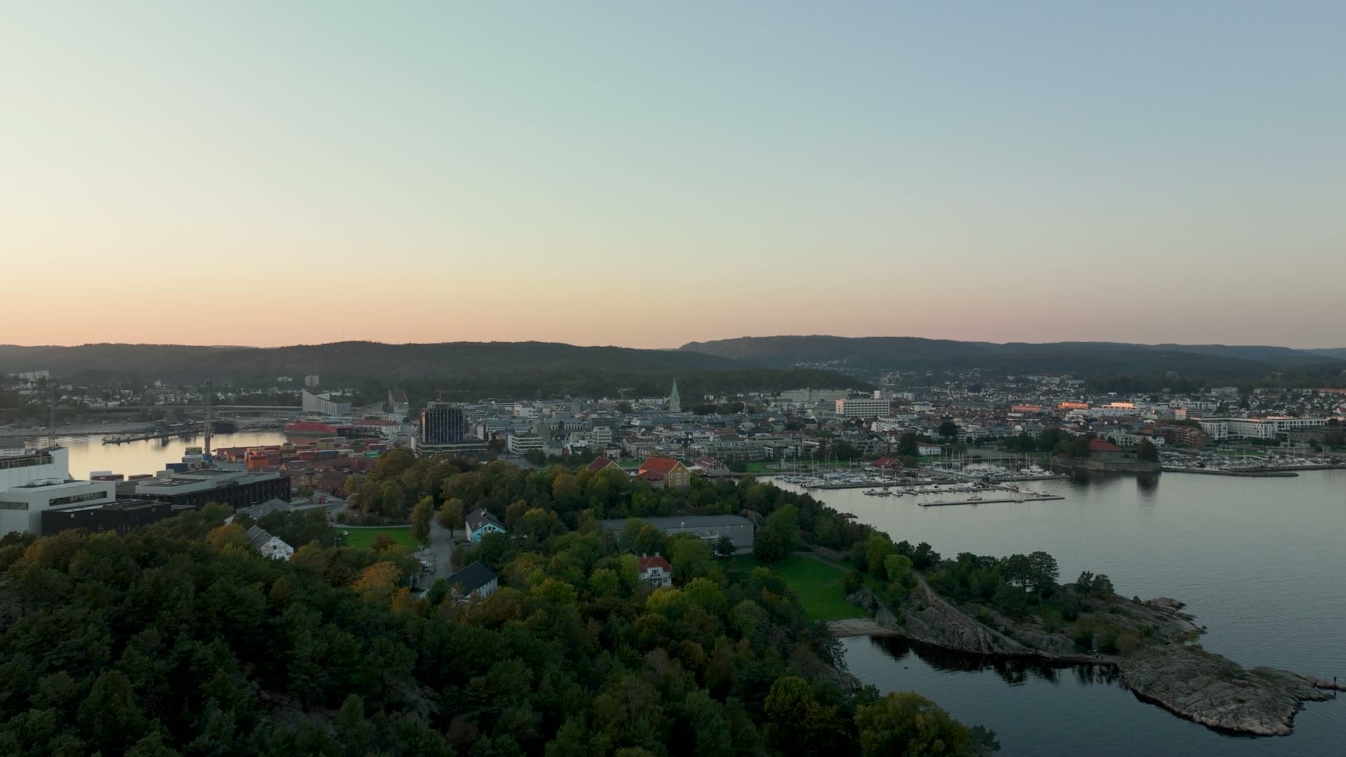 Wooded ridge above marina and town at dusk, Odderøya, Norway