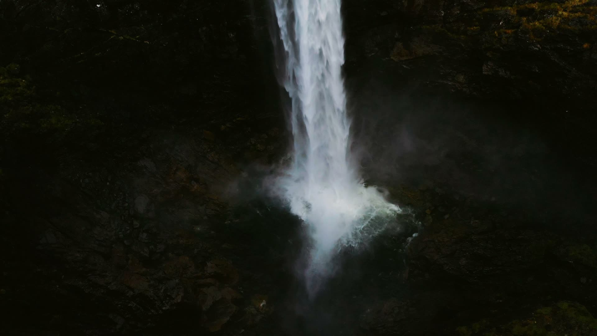 Waterfall plunging into dark rock pool, Månafossen, Norway
