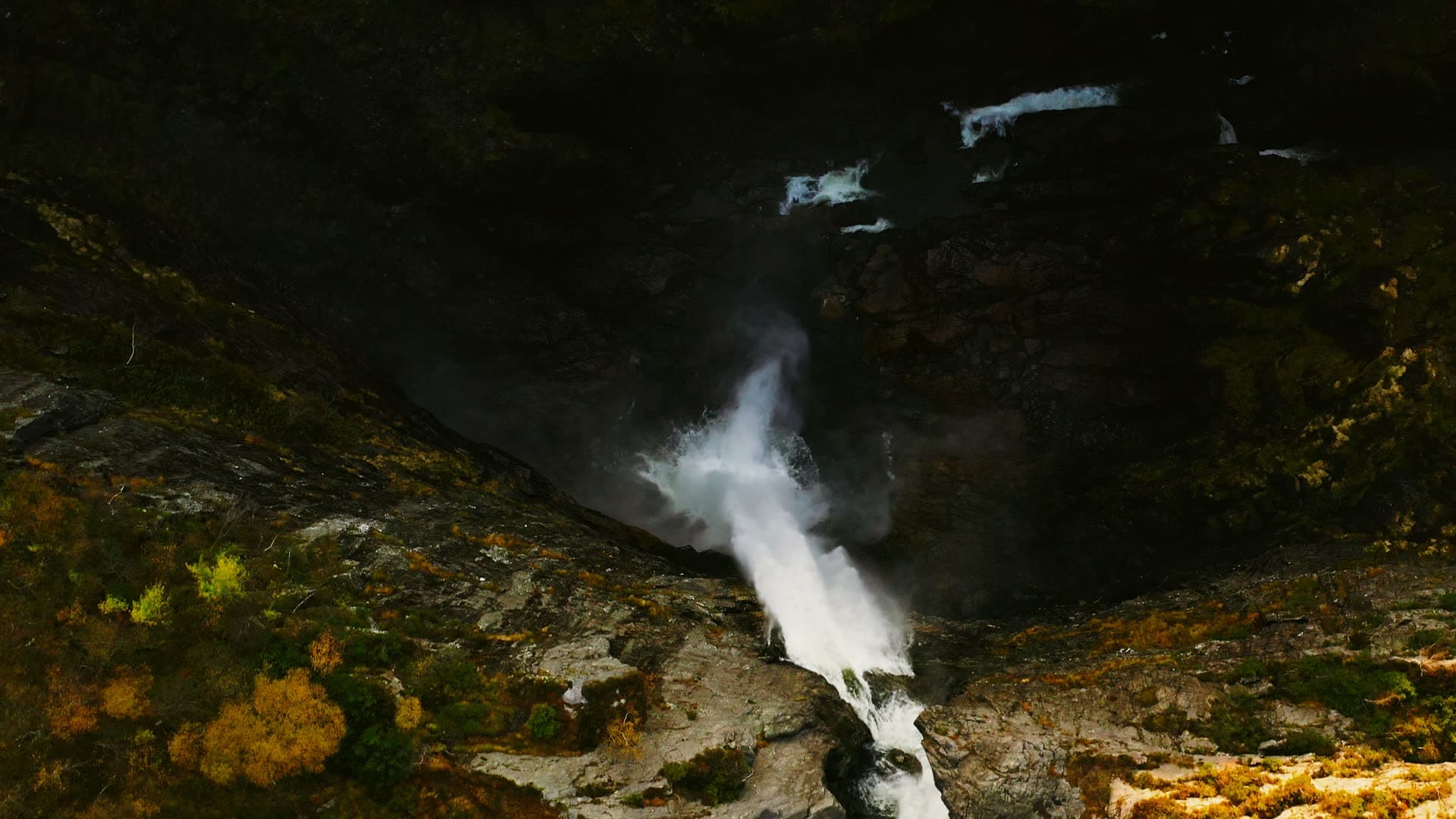 Waterfall spilling into shaded rock gorge, Månafossen, Norway