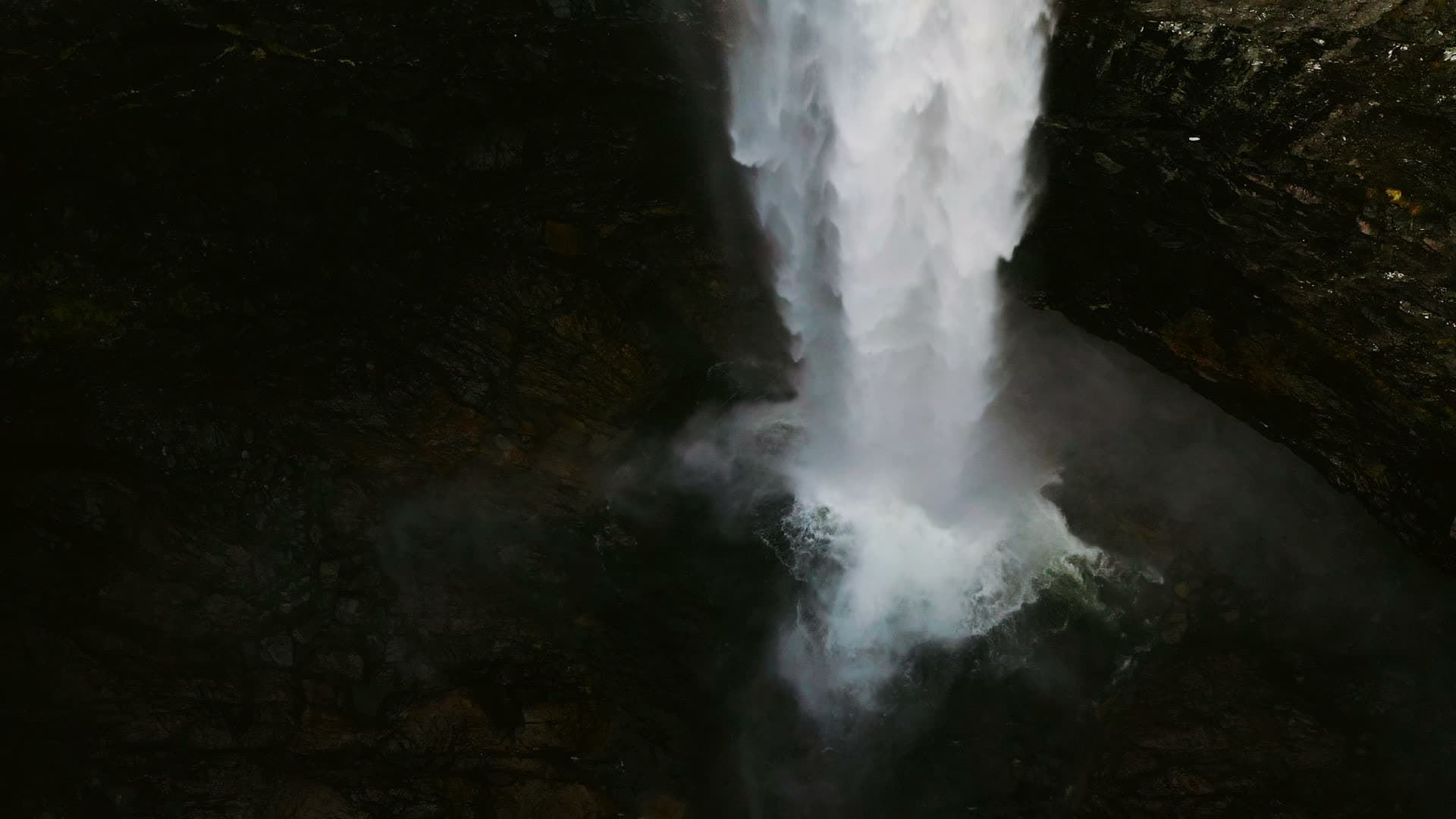 Waterfall hitting dark wet rock basin, Månafossen, Norway