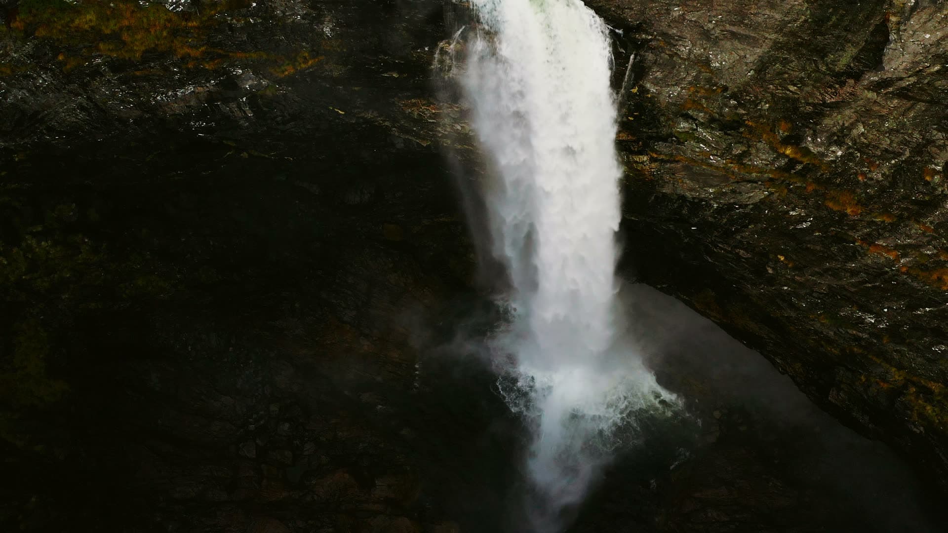 Waterfall dropping into dark rock plunge pool, Månafossen, Norway