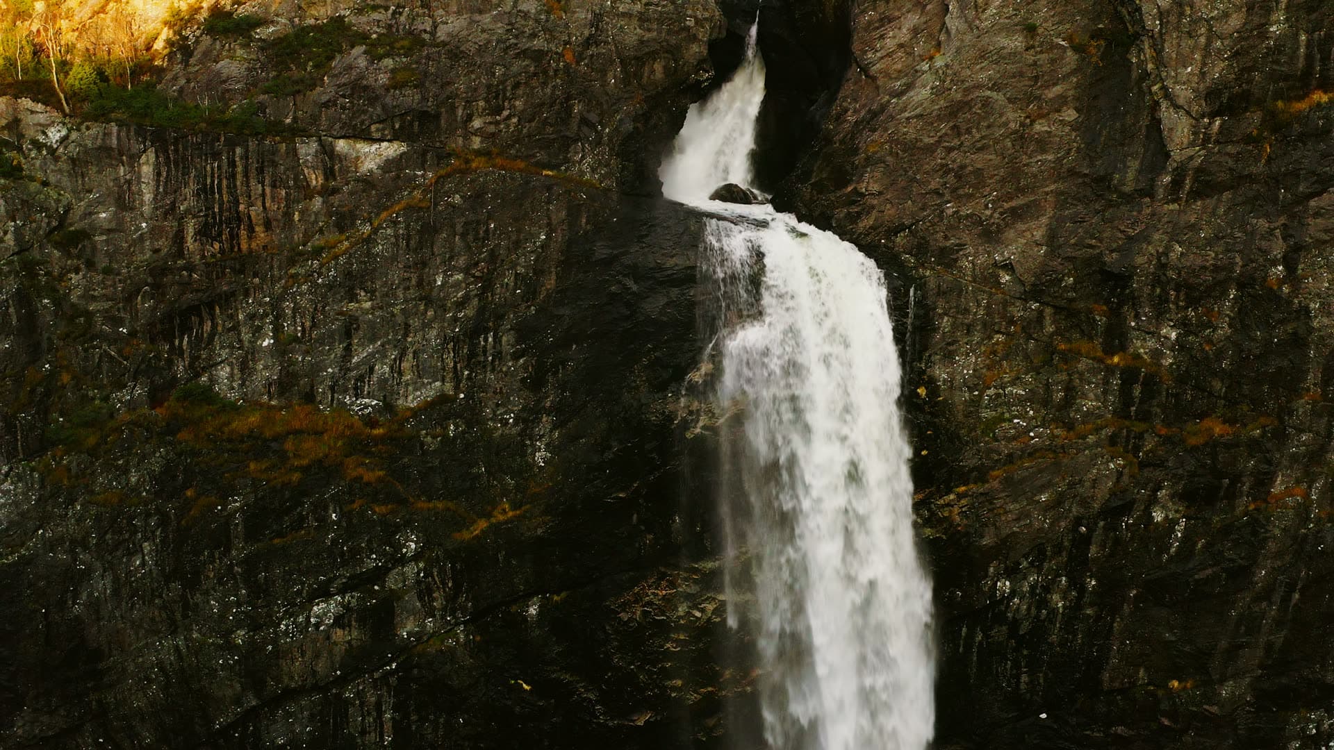 Waterfall dropping through dark rock cleft, Månafossen, Norway