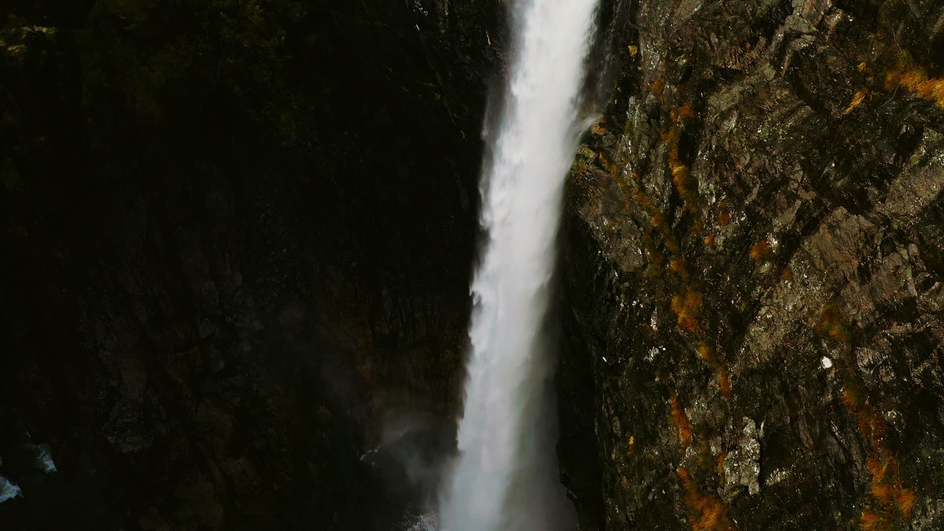 Waterfall plunging down lichen-streaked cliff, Månafossen, Norway
