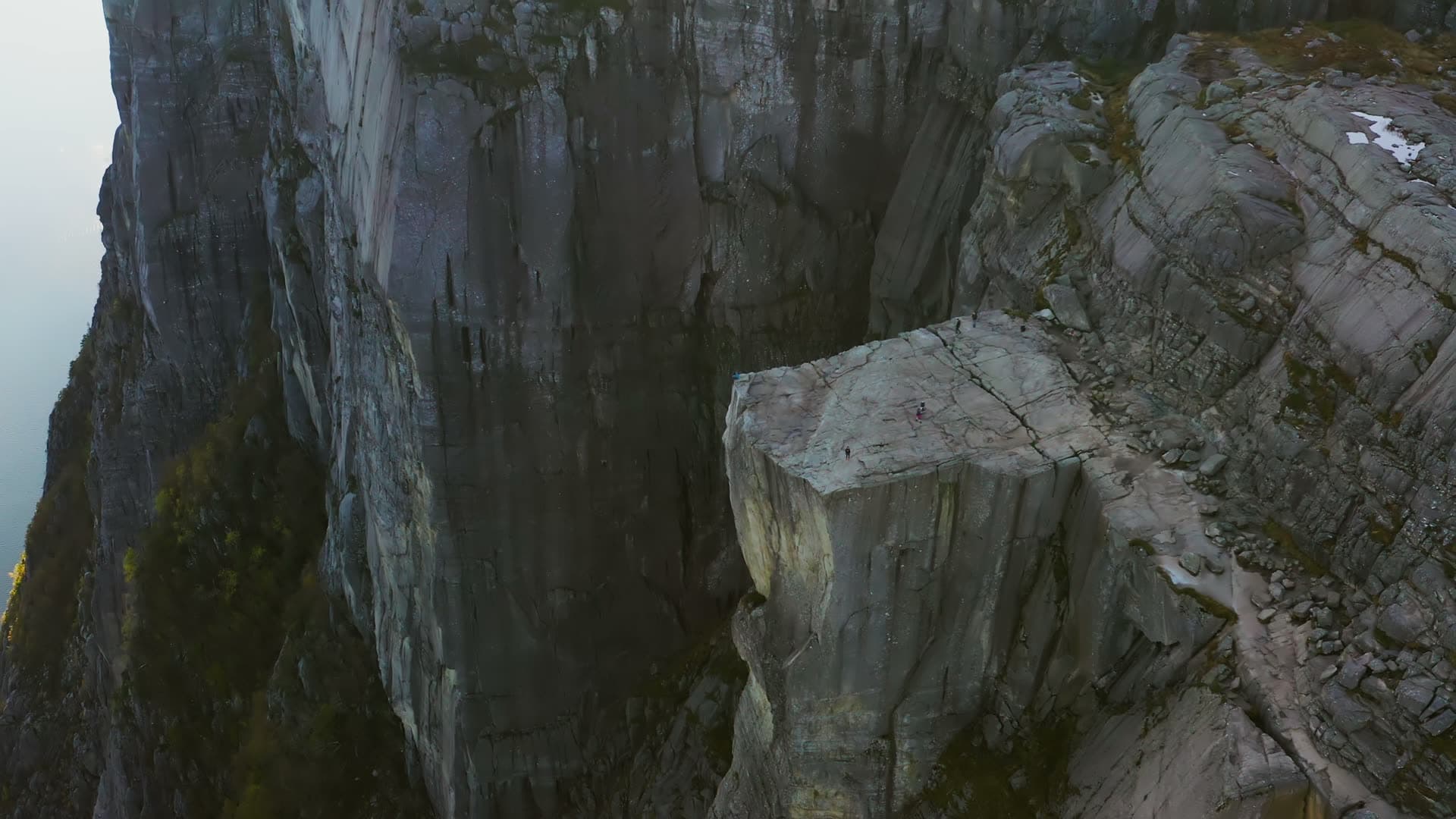 Hikers on flat cliff ledge above sheer wall, Preikestolen, Norway