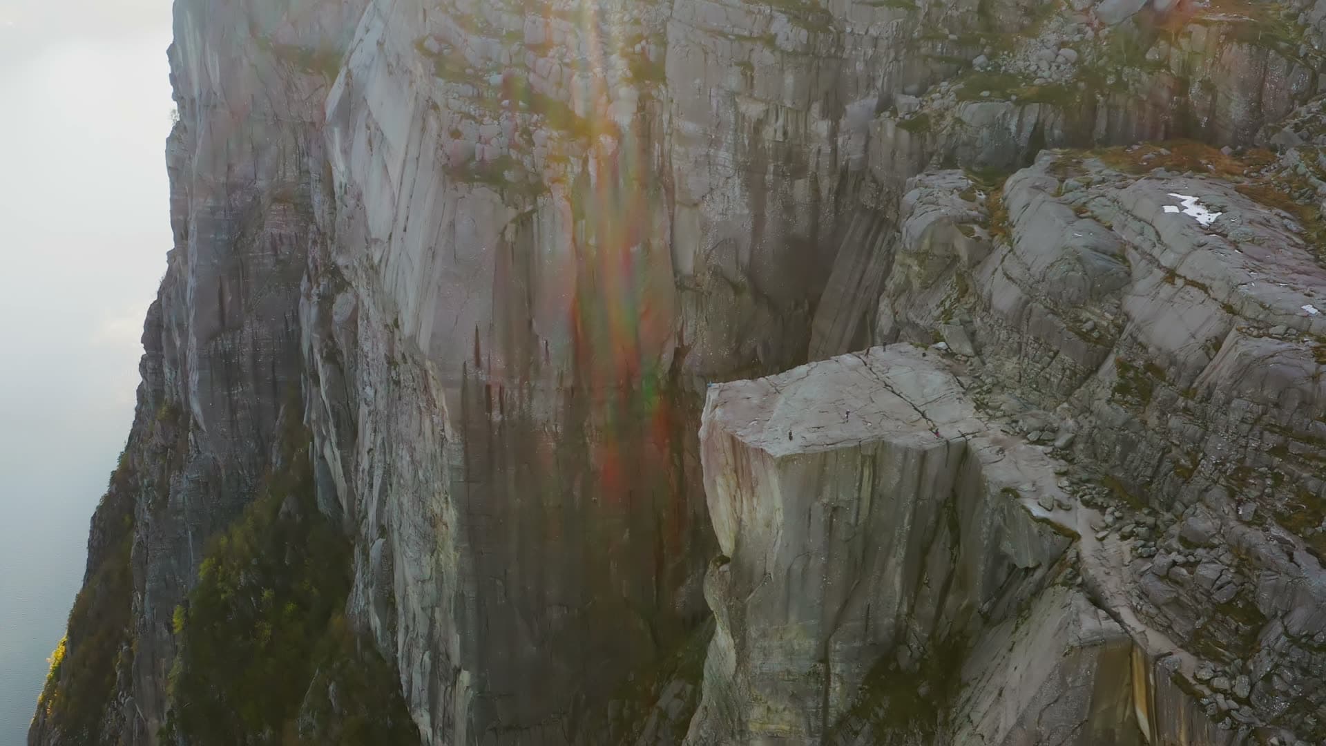Hikers on flat cliff ledge above fjord haze, Preikestolen, Norway