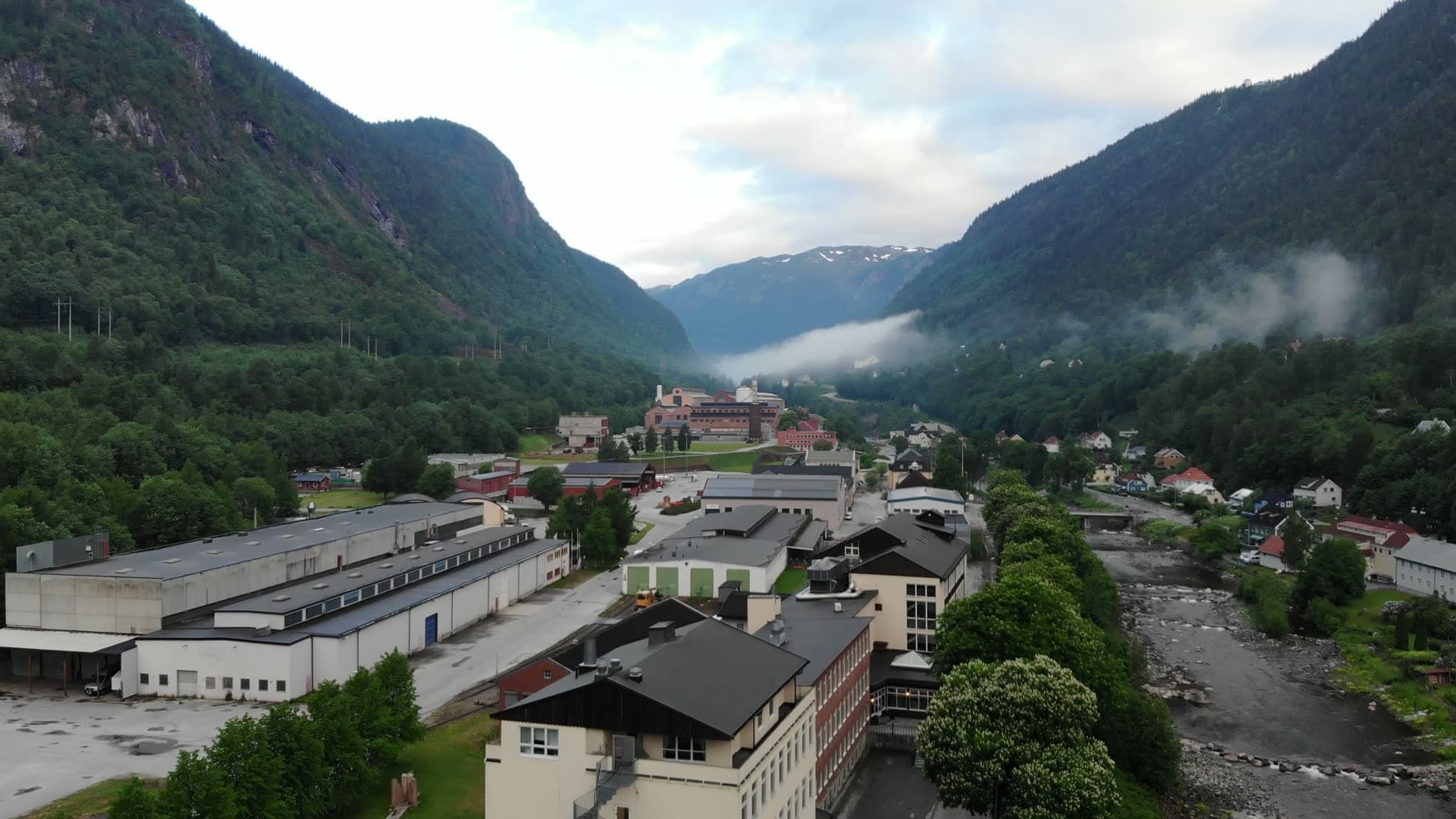 Industrial halls by river, low valley mist, Rjukan, Norway