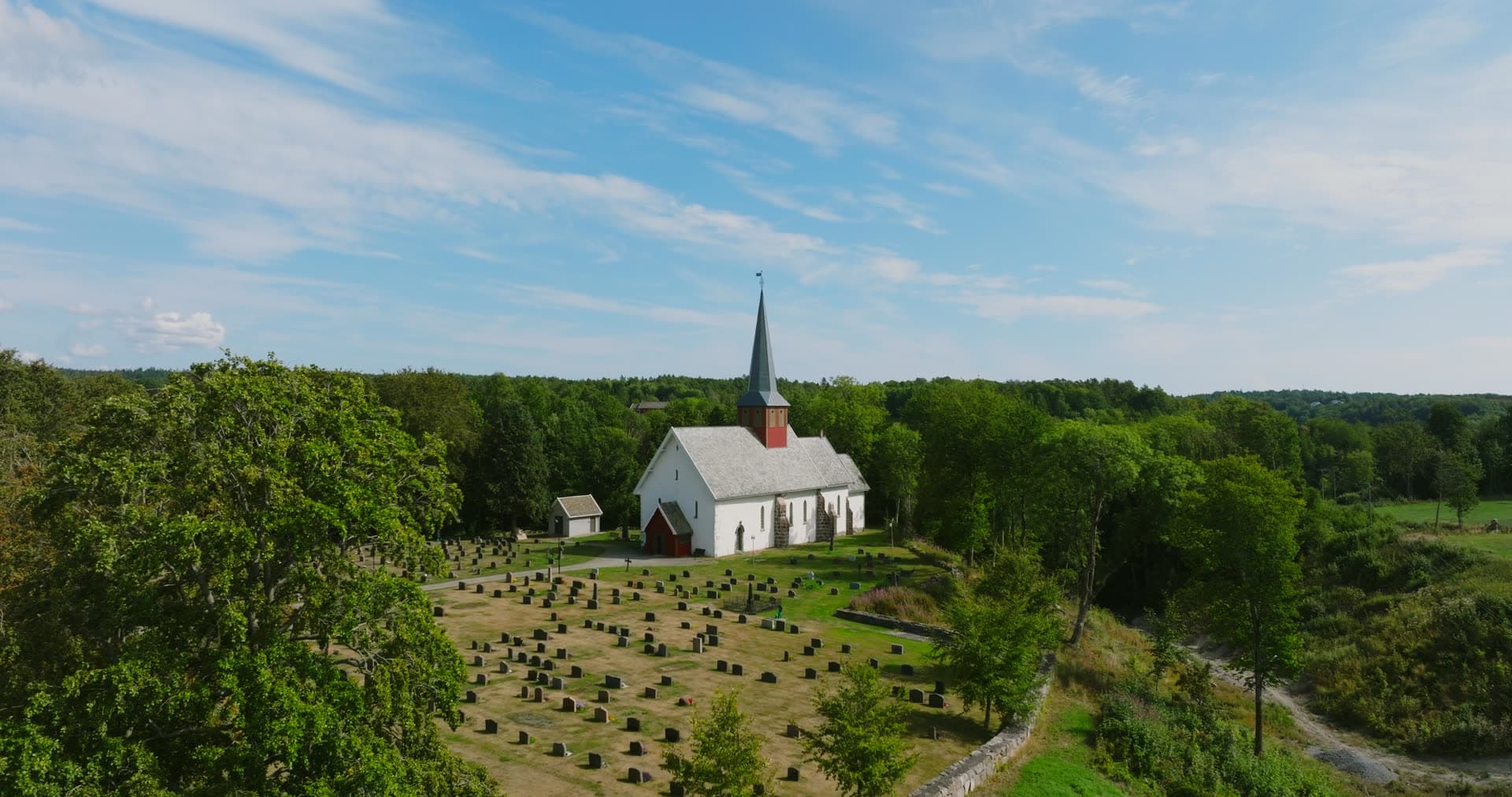 White church and graveyard ringed by trees, Rykene, Norway