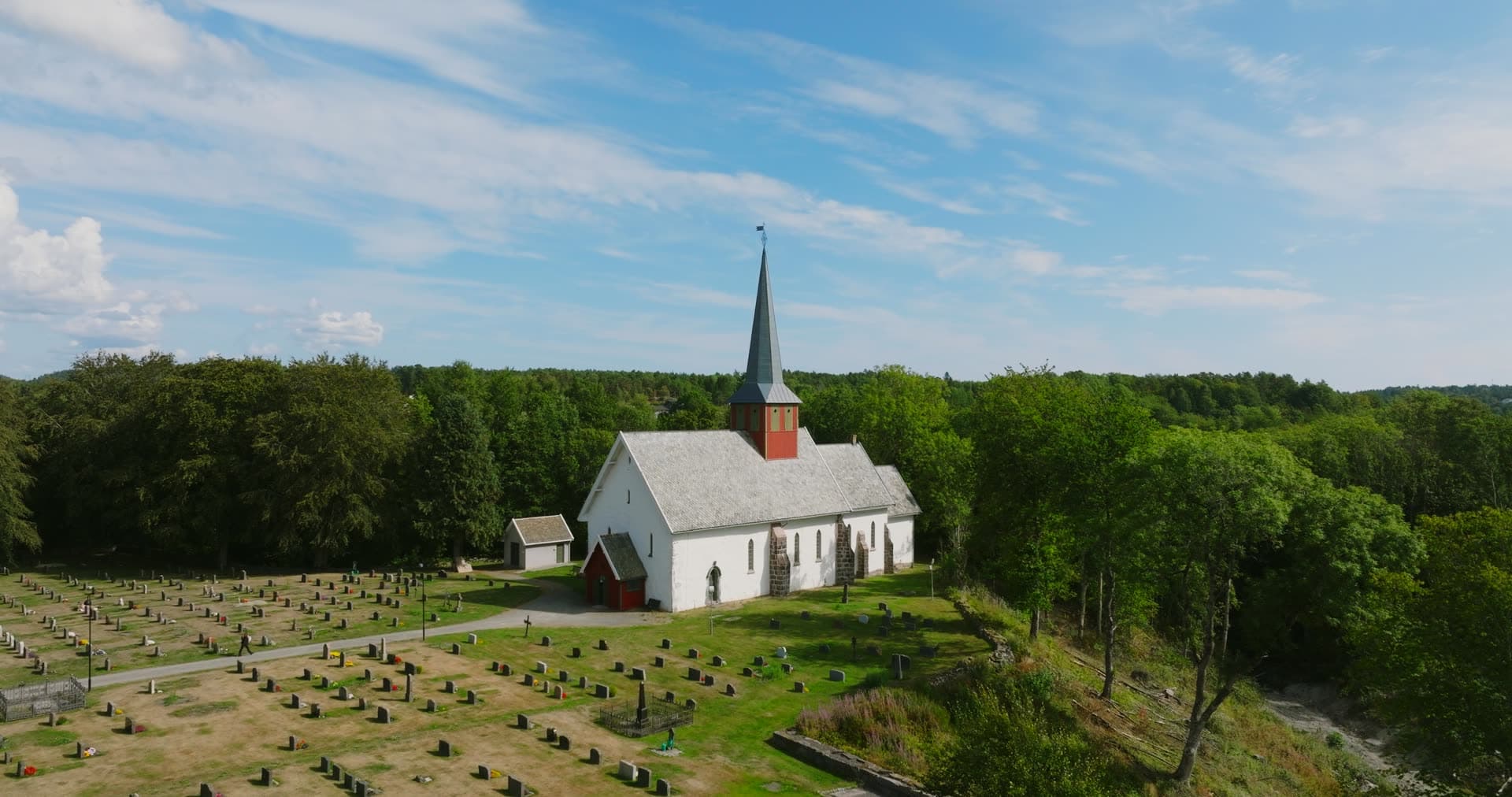 White stone church and graveyard by woods, Rykene, Norway
